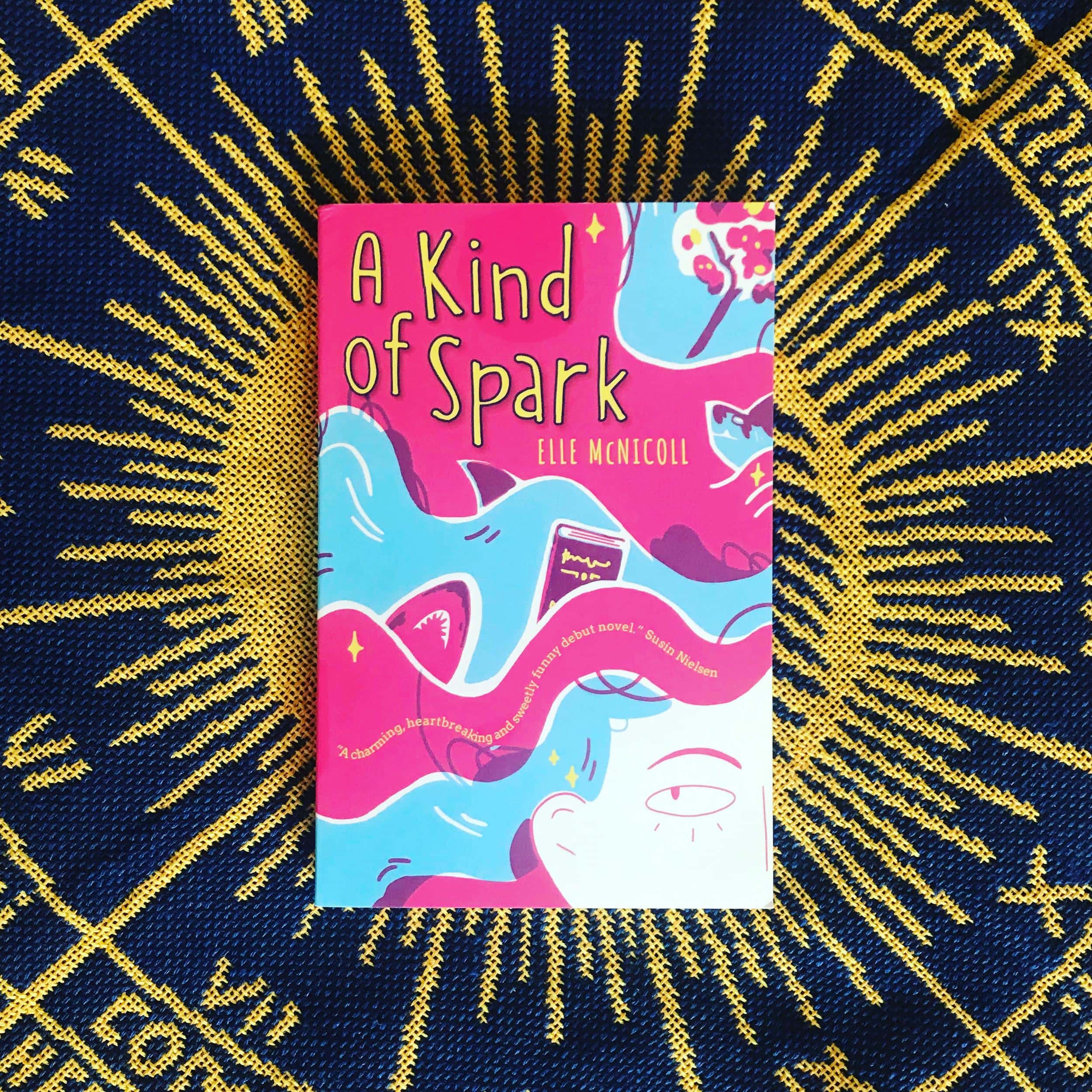The cover of a Kind of Spark by Elle McNicoll. The cover shows the corner of Addie's eye in the bottom right, with hair flowing over the rest of the cover. There are sharks in her hair, plus a dictionary and a tree.