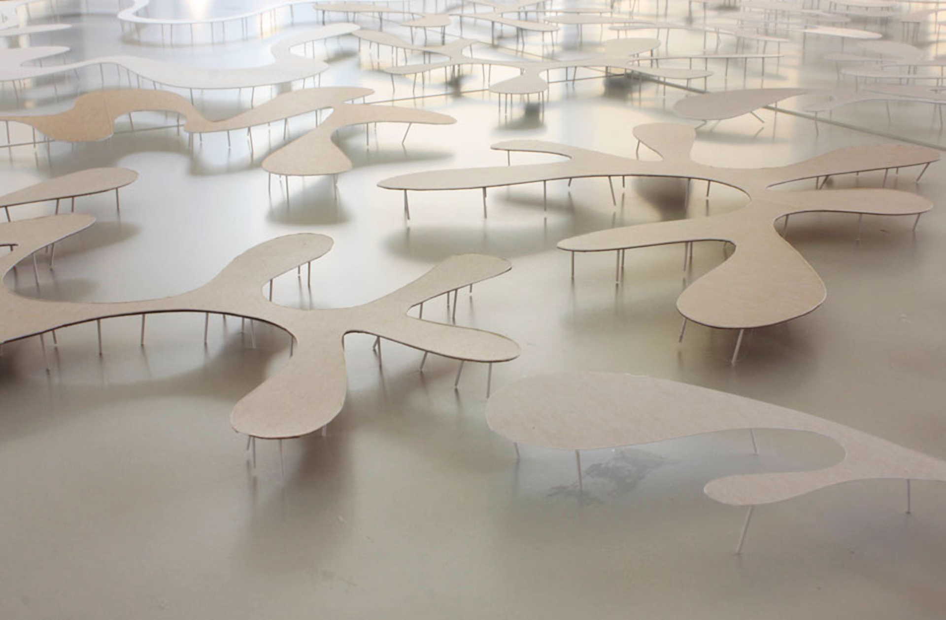 Working with several spatial studies our preoccupation with a long linear table shaped obstructively gradually shifted towards a meandering landscape which encompasses the visitor.