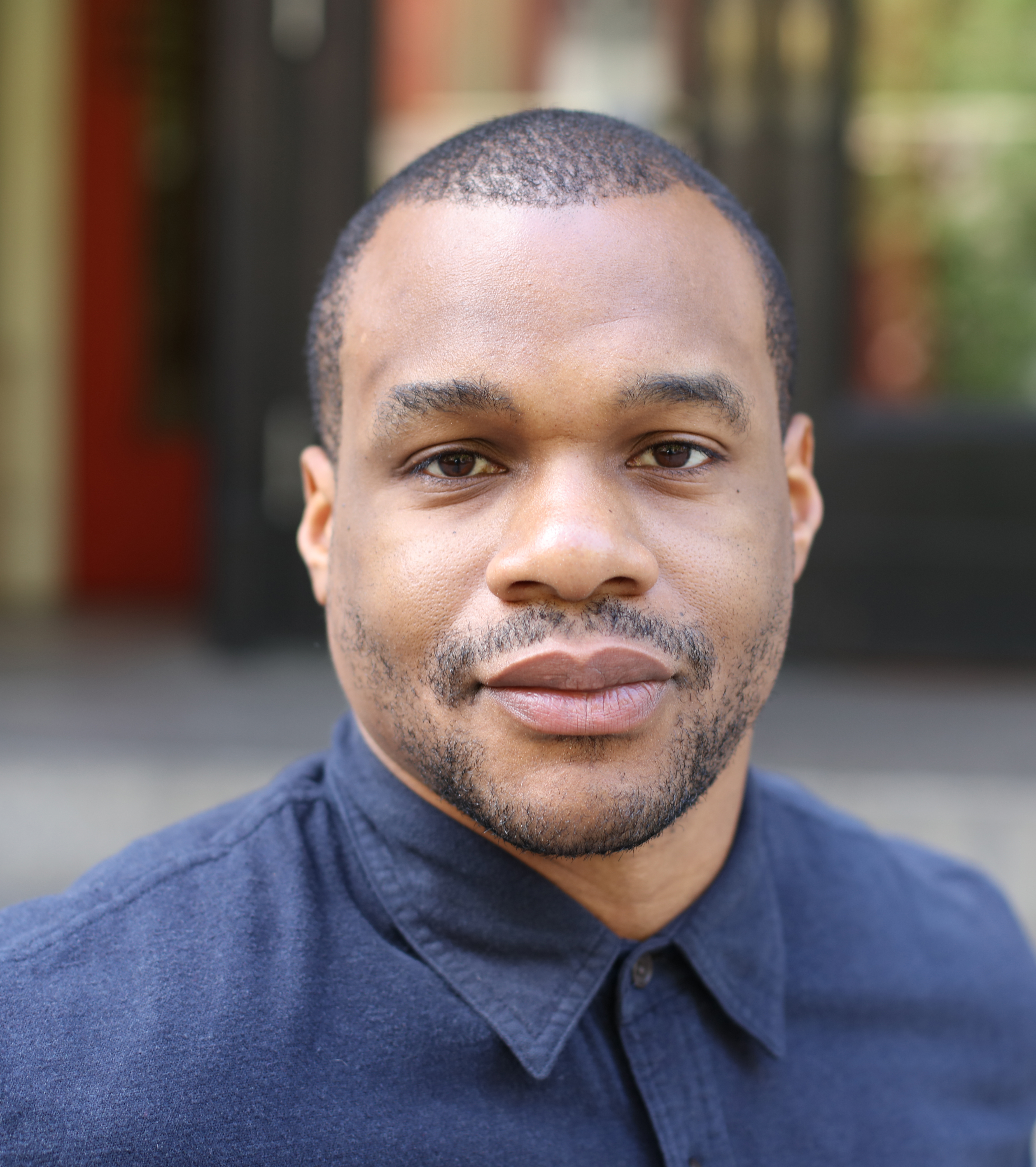 A headshot of artist, Noel W Anderson, who looks directly at the camera with a slight smile, and a blue button up shift.