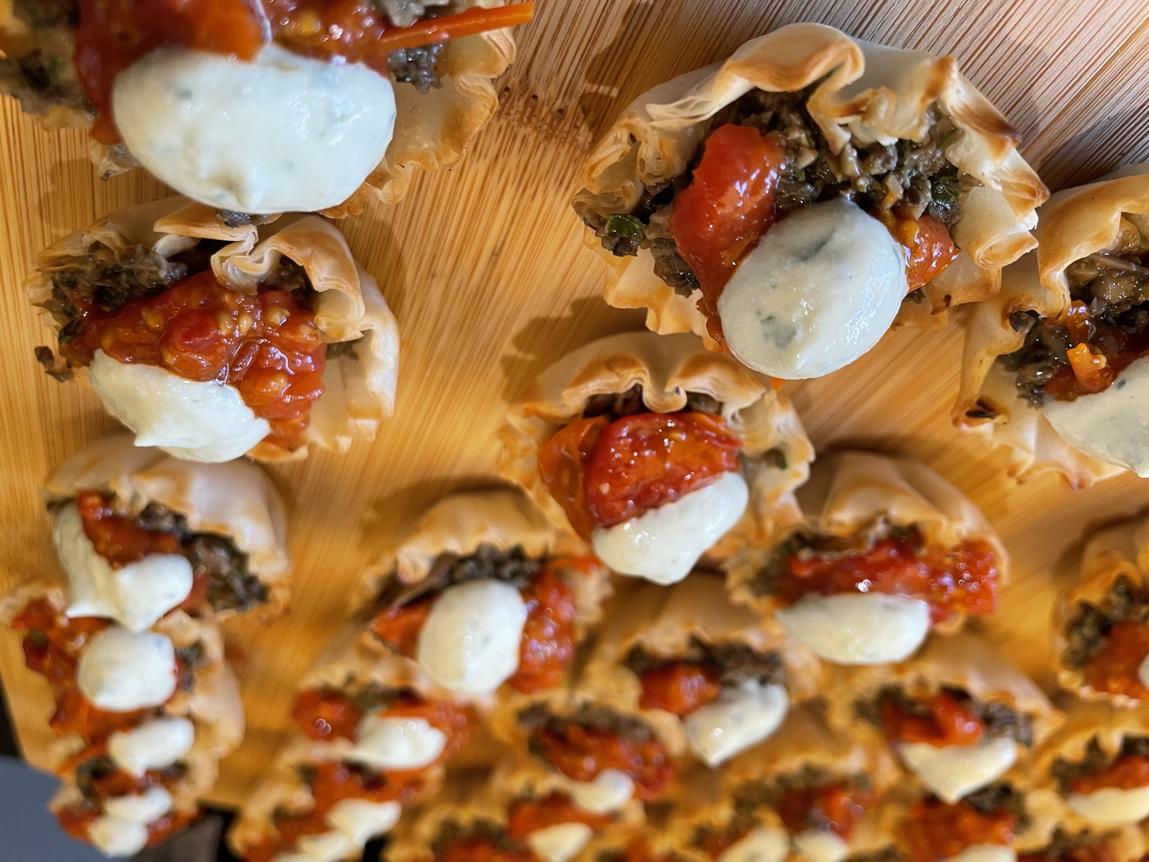 Garden Filo Cups filled with pesto mushroom duxelle, roasted grape tomato, garlic confit, & a dot of ricotta