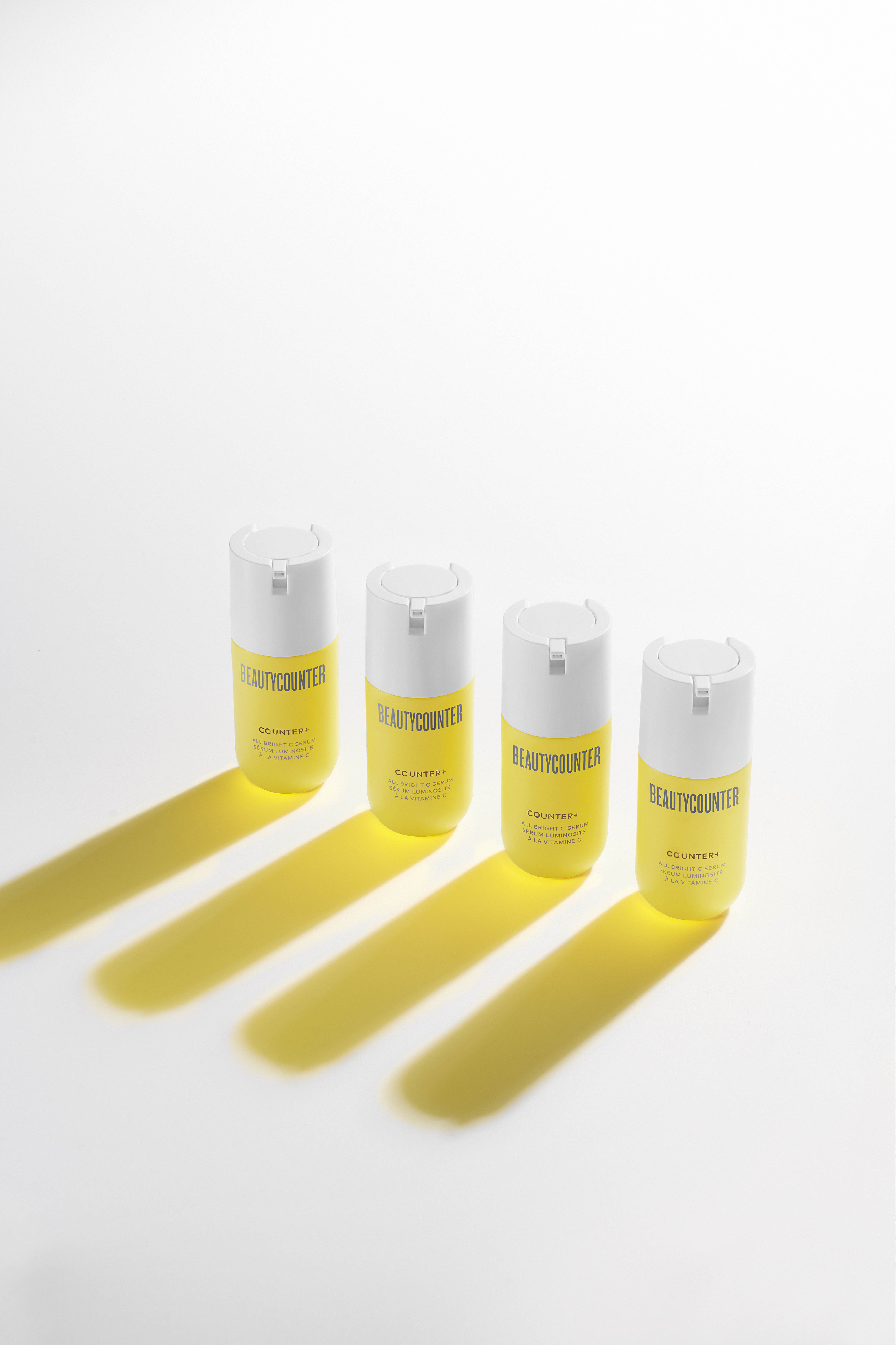 KMA stylist Sara Wacksman designs set for photo of Beauty Counter yellow serum bottles with white background and shadows 
