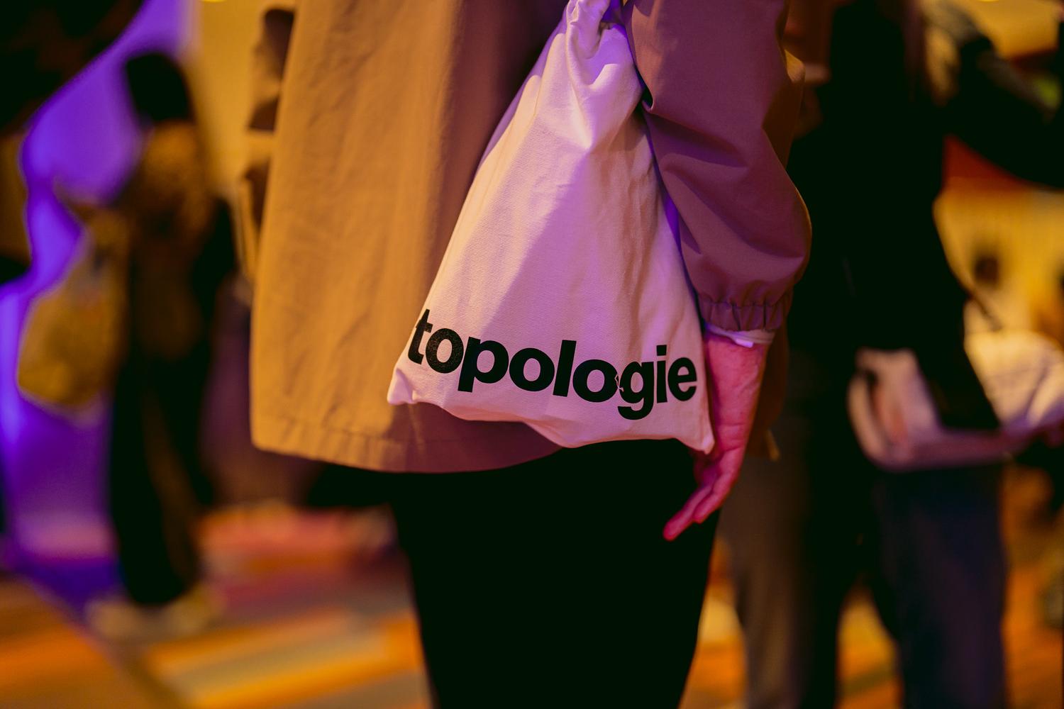 Topologie tote bag worn by an attendee at AVA London 2025, highlighting the brand’s partnership with the event.