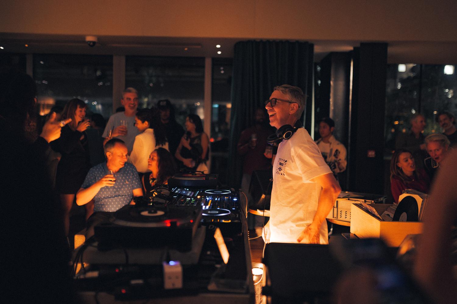 Close-up of Gilles Peterson smiling while DJing at the Paired × Tate Modern event, surrounded by guests enjoying the night