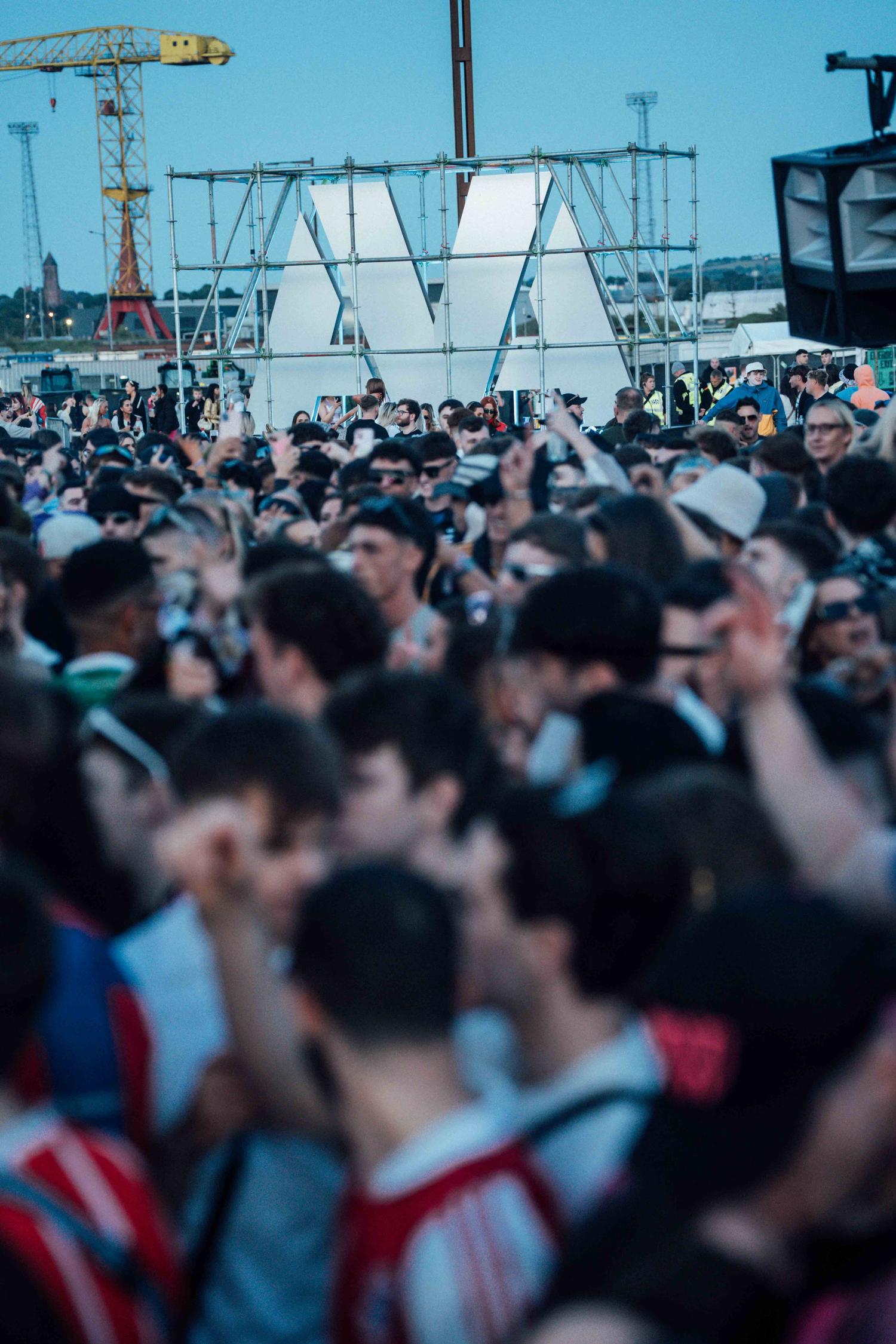 Festival crowd at AVA Festival 2025 daytime event with AVA logo installation in background