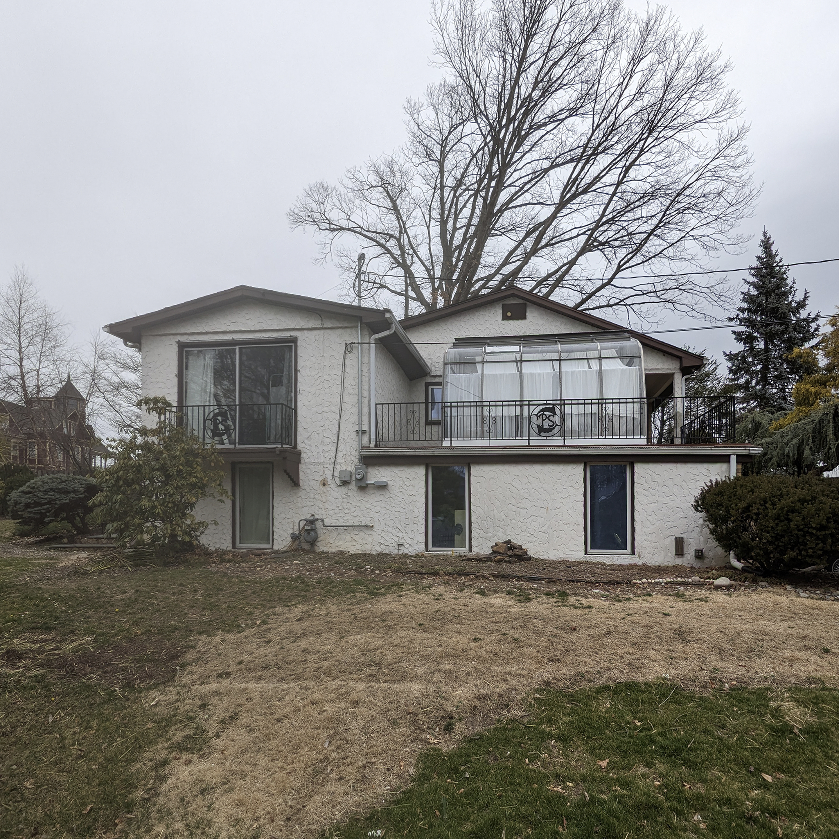 Original exterior photograph of the Atlantic Highlands Ranch, showing the dated stucco, metal railing, and existing window configuration before the exterior cladding and finishing work began.