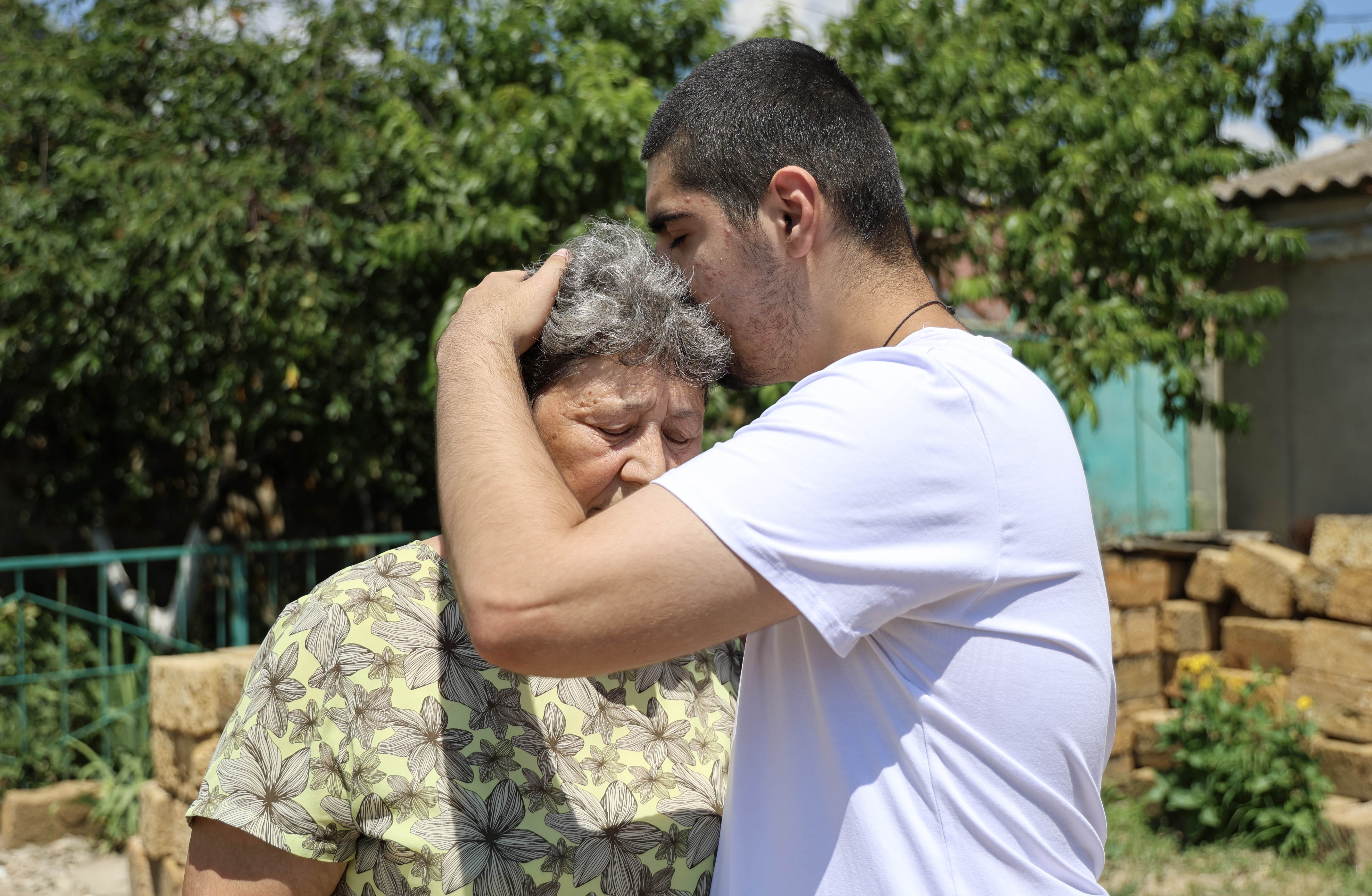 Artem Parakonnyi, who was taken by the Russians without his or his family’s consent, embraces his grandmother Nina Medynska in front of their home.