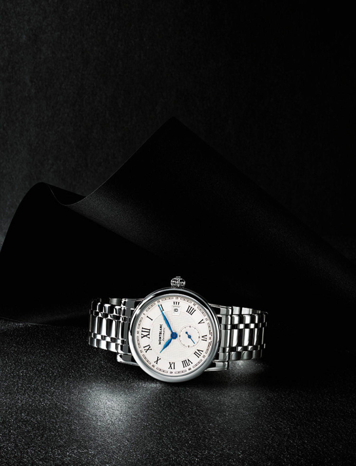 KMA stylist Sara Wacksman designs set for a photo of a silver watch resting on a shiny black surface