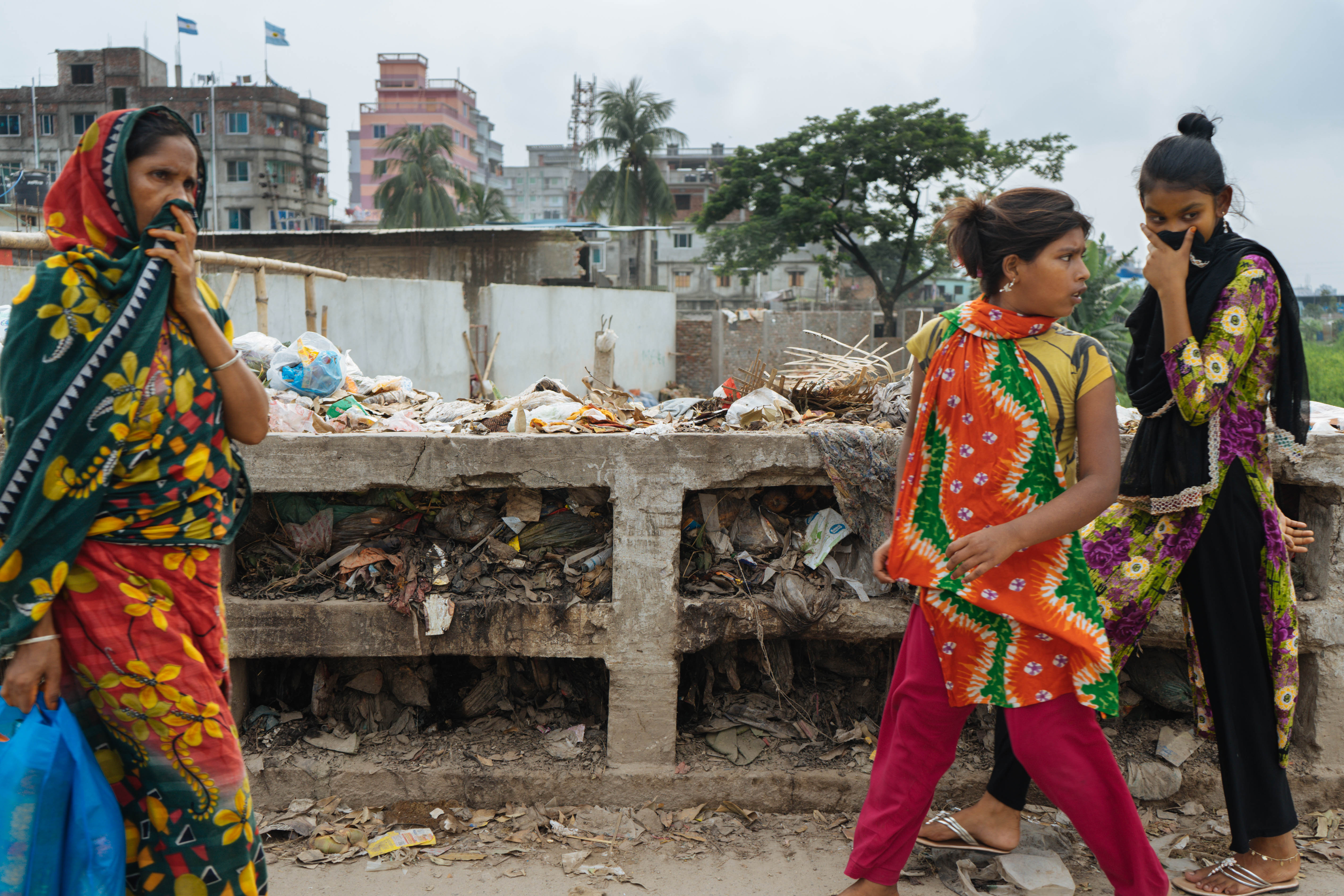 Collaboration with Shamsul Palash, documenting environmental injustices in Kamrangirchar (an industrial/waste area southwest of Dhaka city). Here, women cover their mouth and nose as they walk across a bridge over a channel of burning trash.