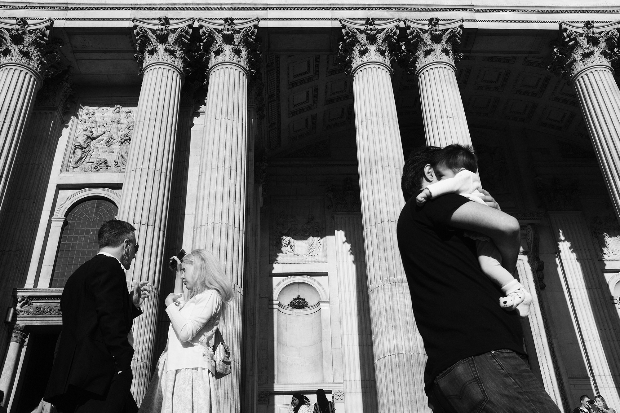 Philippe-Sarfati-early-work-photography-photographer-street-documentary-black-and-white-london-uk-st-paul-cathedral-columns-classic-architecture-monumental-church-couple-talking-man-walking-baby