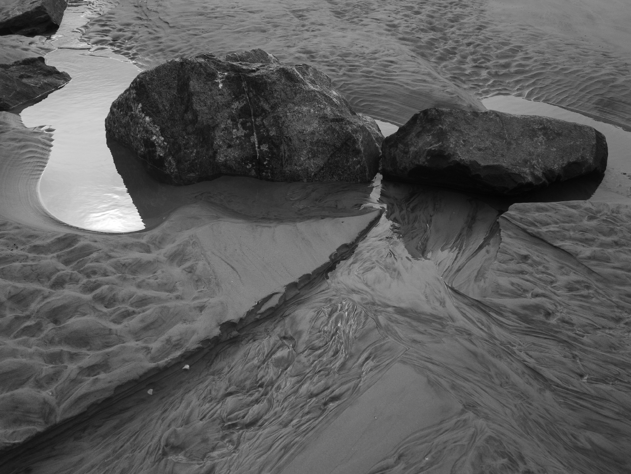 Black/white photography by Amy Schuessler, 2020: two large rocks on a sandy beach