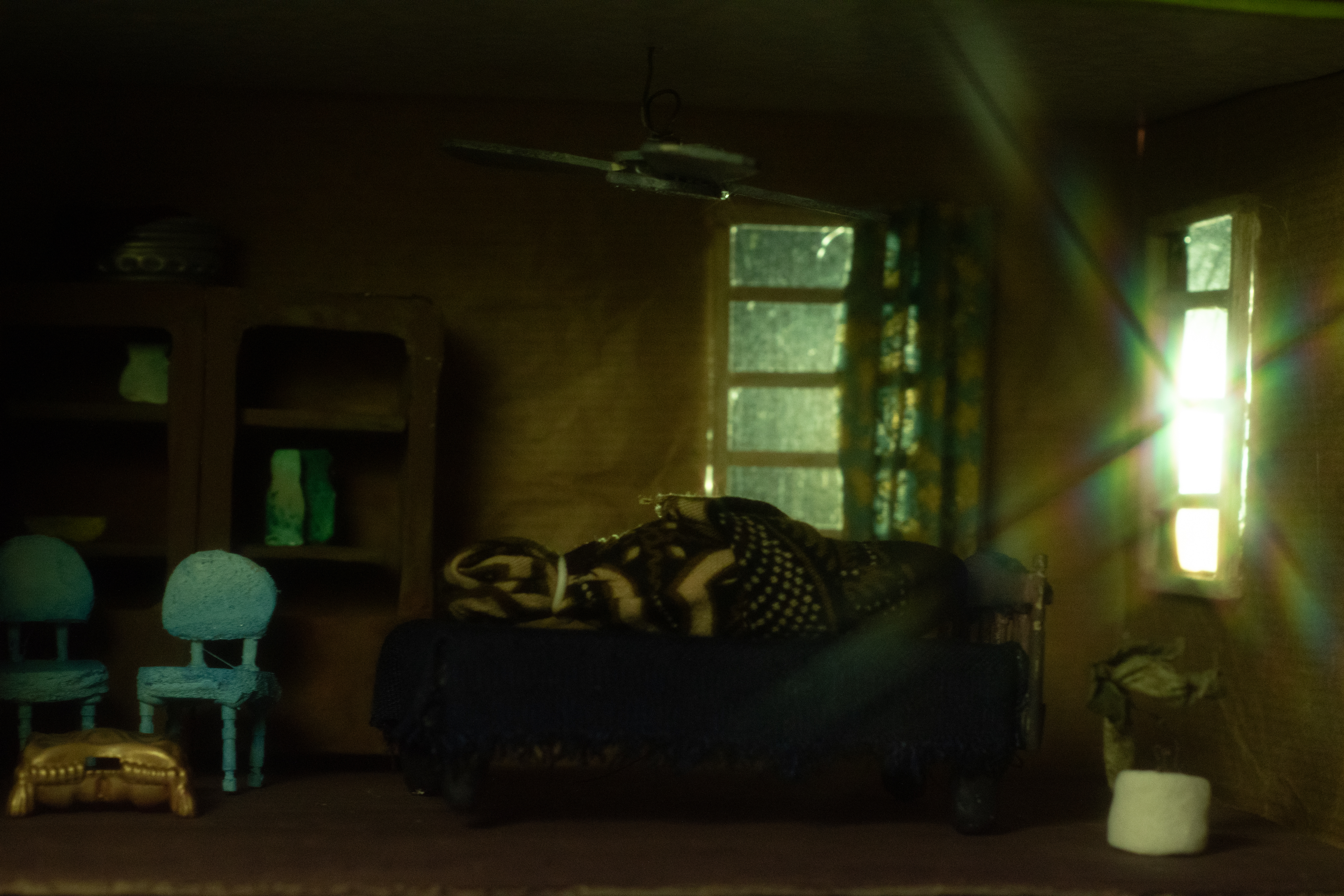 Image 1 of 4: A dimly lit diorama of a shrouded body on a bed
