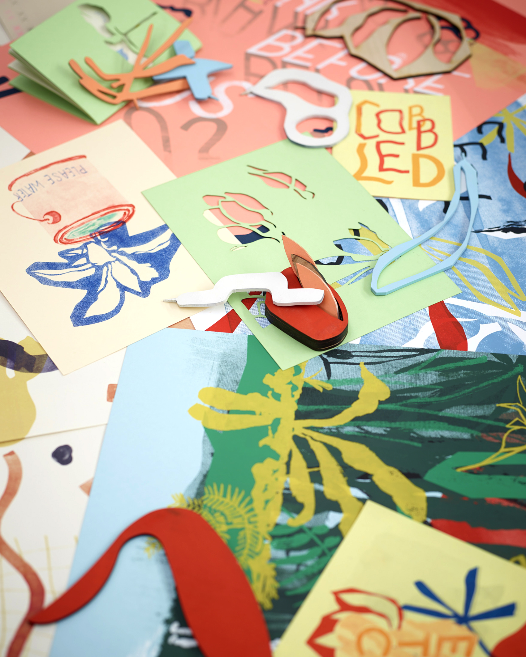 Pile of colorful prints and laser cut shapes of Jimmy Mezei's work.