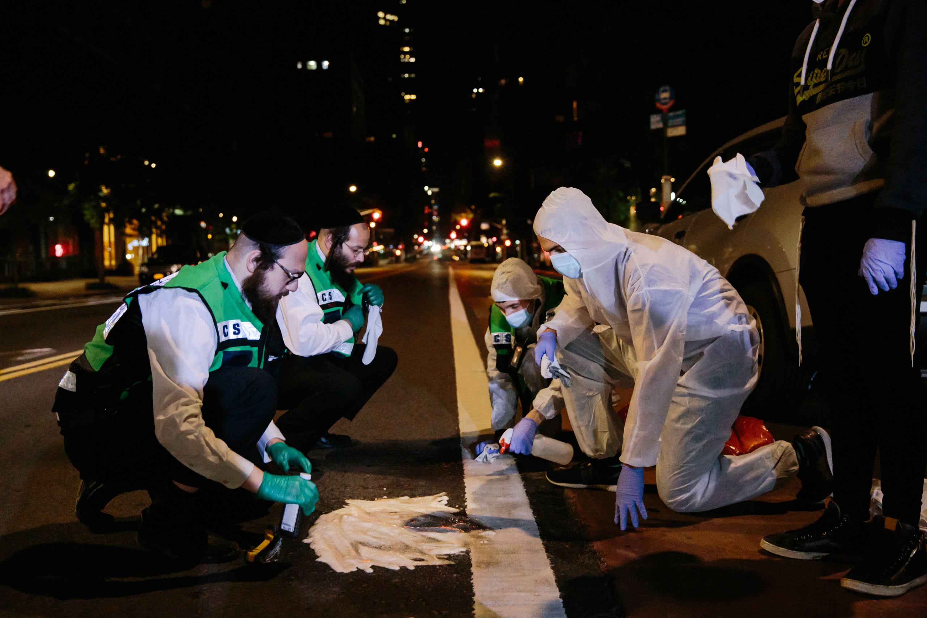 A crew of Chesed Shel Emes workers clean up after the body of a Jewish man who jumped to his death was removed from the scene in midtown Manhattan. According to Jewish law any spilled blood must be cleaned following death, and any remains must be buried with the deceased.