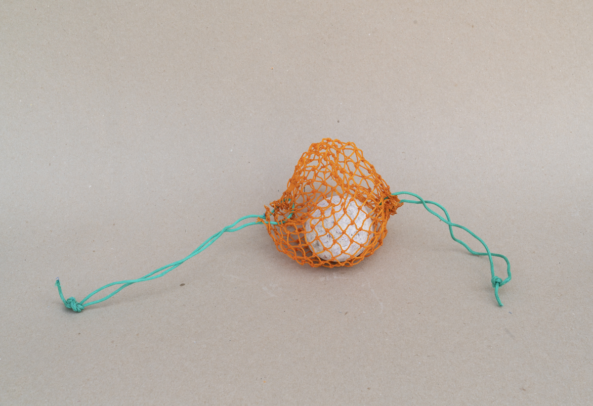 Entice, 2018, Found bait bag and rock, 5.75 x 23 x 7 inches