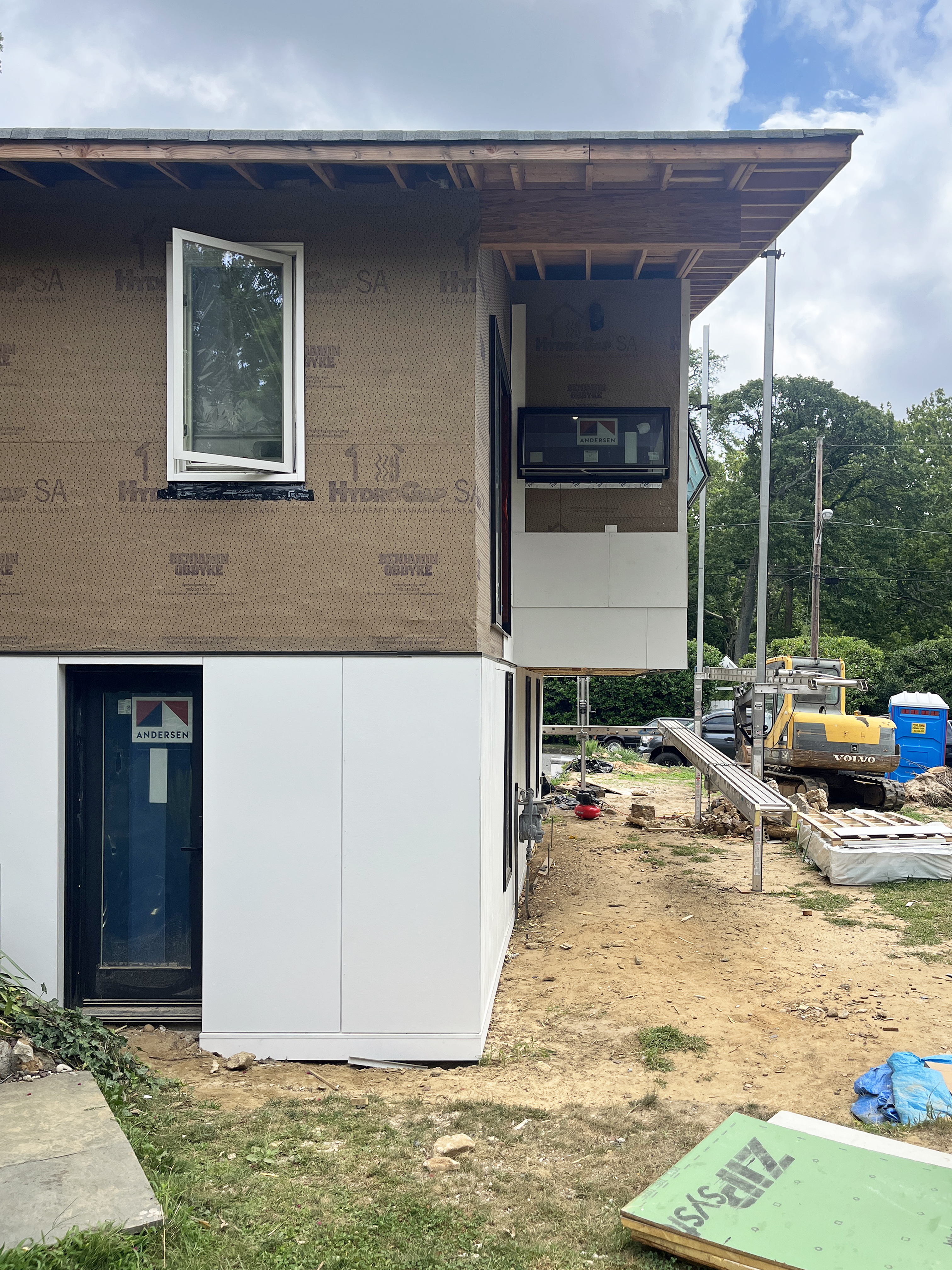Construction photograph showing progress on the Atlantic Highlands Ranch Reno entry, detailing the newly installed wood staircase and white exterior cladding panels.