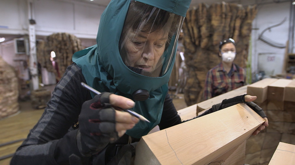 Von Rydingsvard drawing cut lines on 4x4" cedar beams, which will later be cut with a chainsaw by her assistants, 2015.