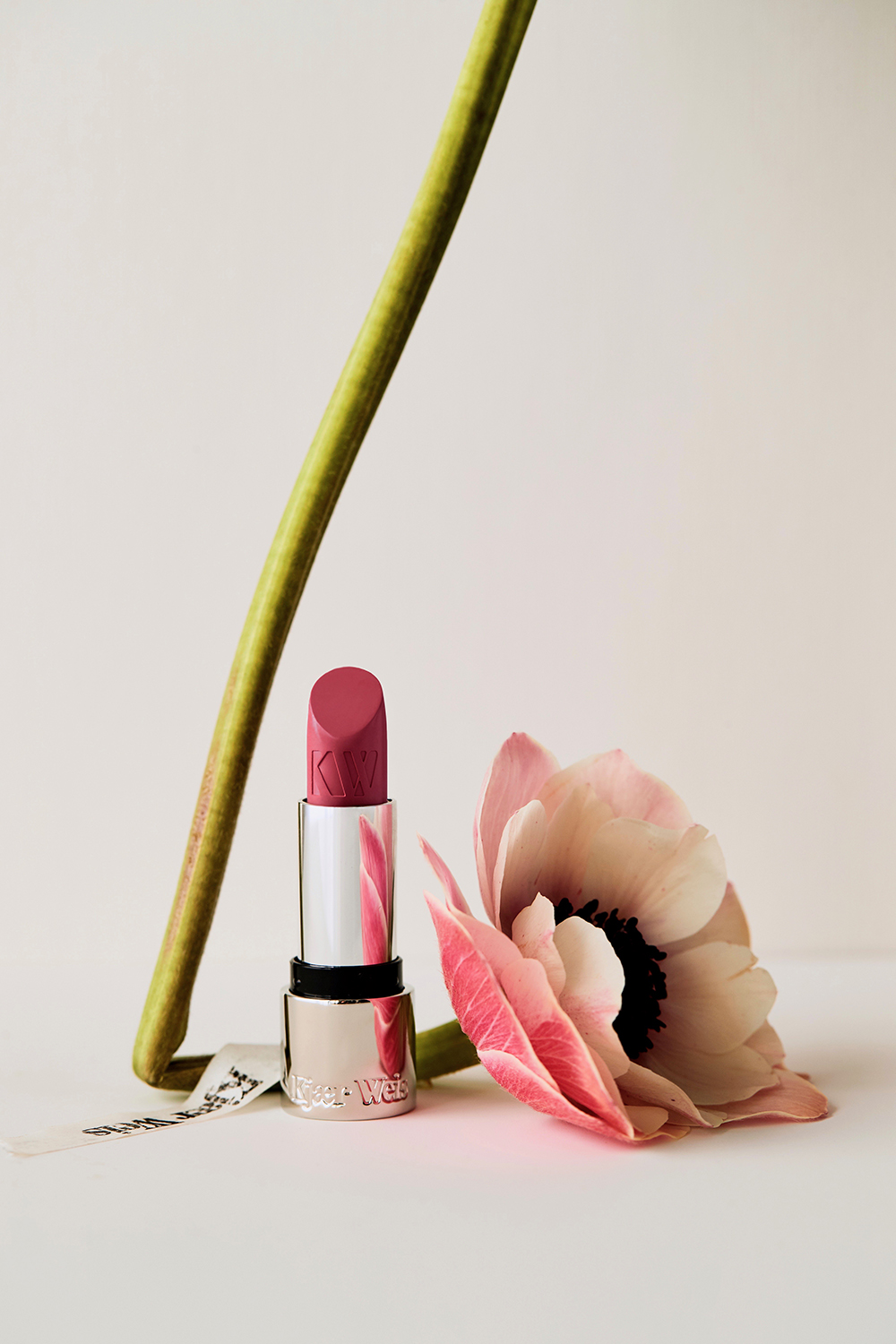 KMA stylist Sara Wacksman designs set for a photo of a pink flower on a white background with pink lipstick for Kjaer Weis