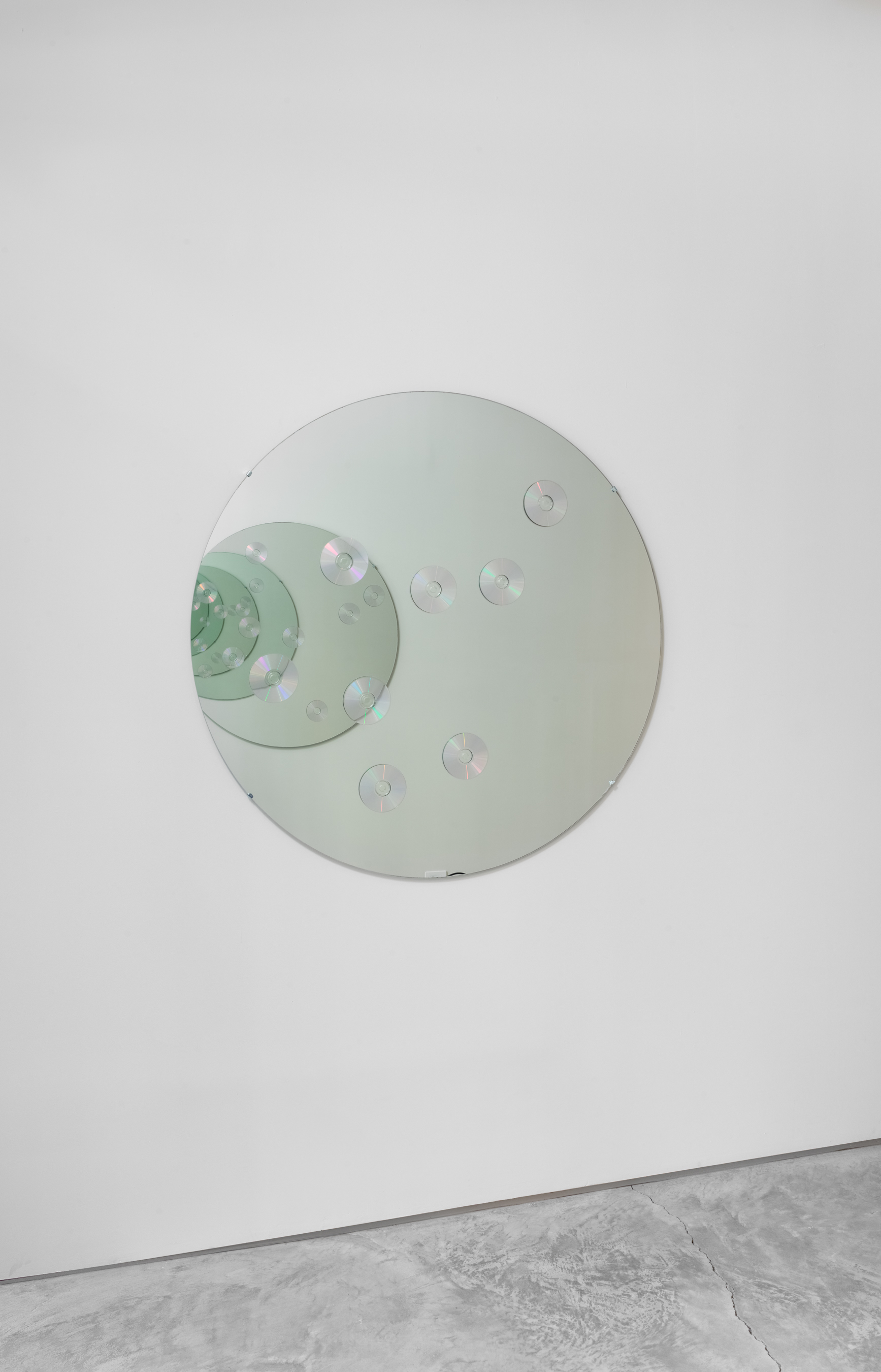 Installation shot, YOU STAND ON THE GROUND FLOOR curated by Harriet Salmon and Jesse Penridge. Christian Marclay, Feedback, 1994. Two circular mirrors with compact discs, 48 inches in diameter. (Credit: Jason Mandella)