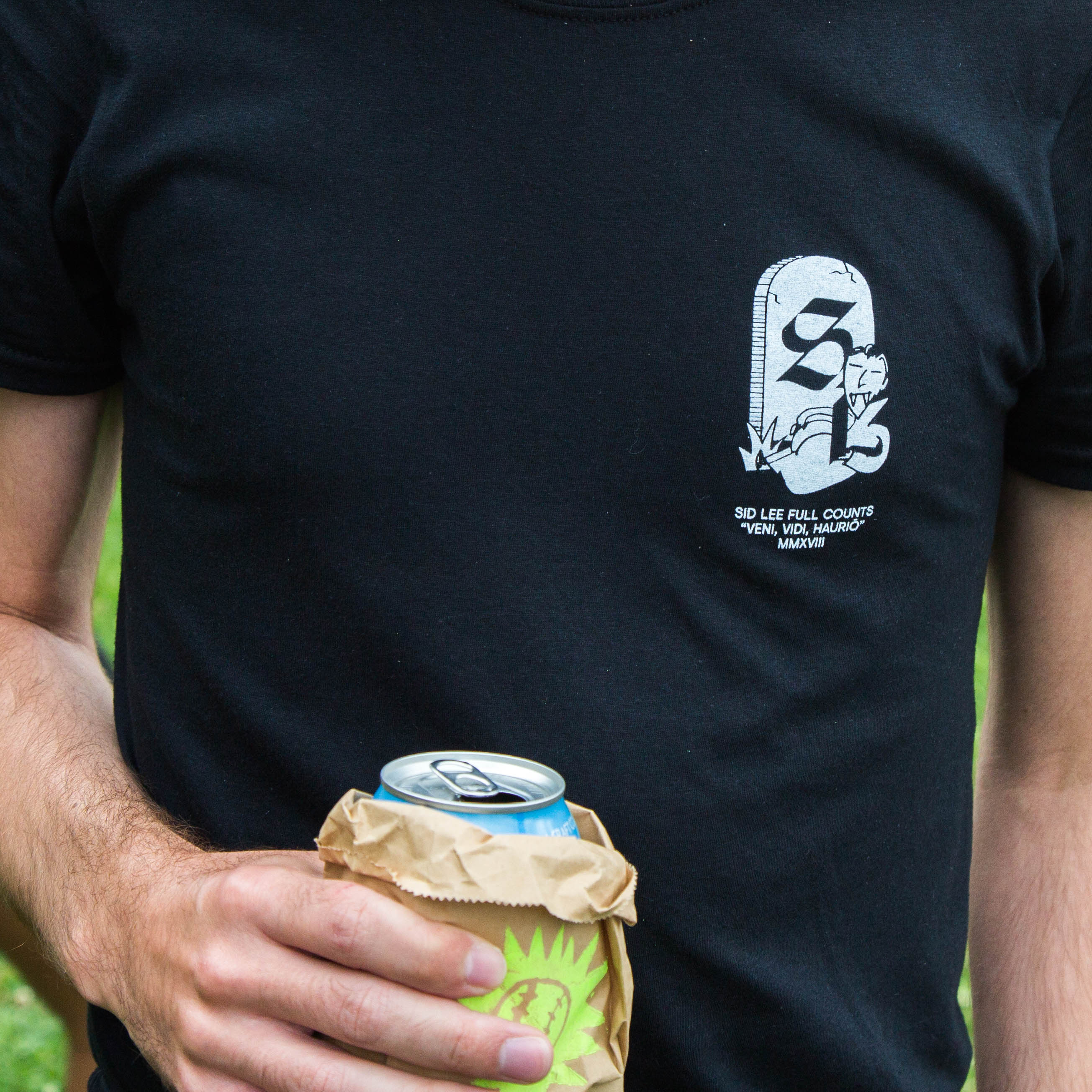 Close up photo of the tshirt. There is a small logo with the 'full count' sitting in front of a tombstone. Under it reads: 'veni, vidi, haurio' meaning 'we came, we saw, we lost.'