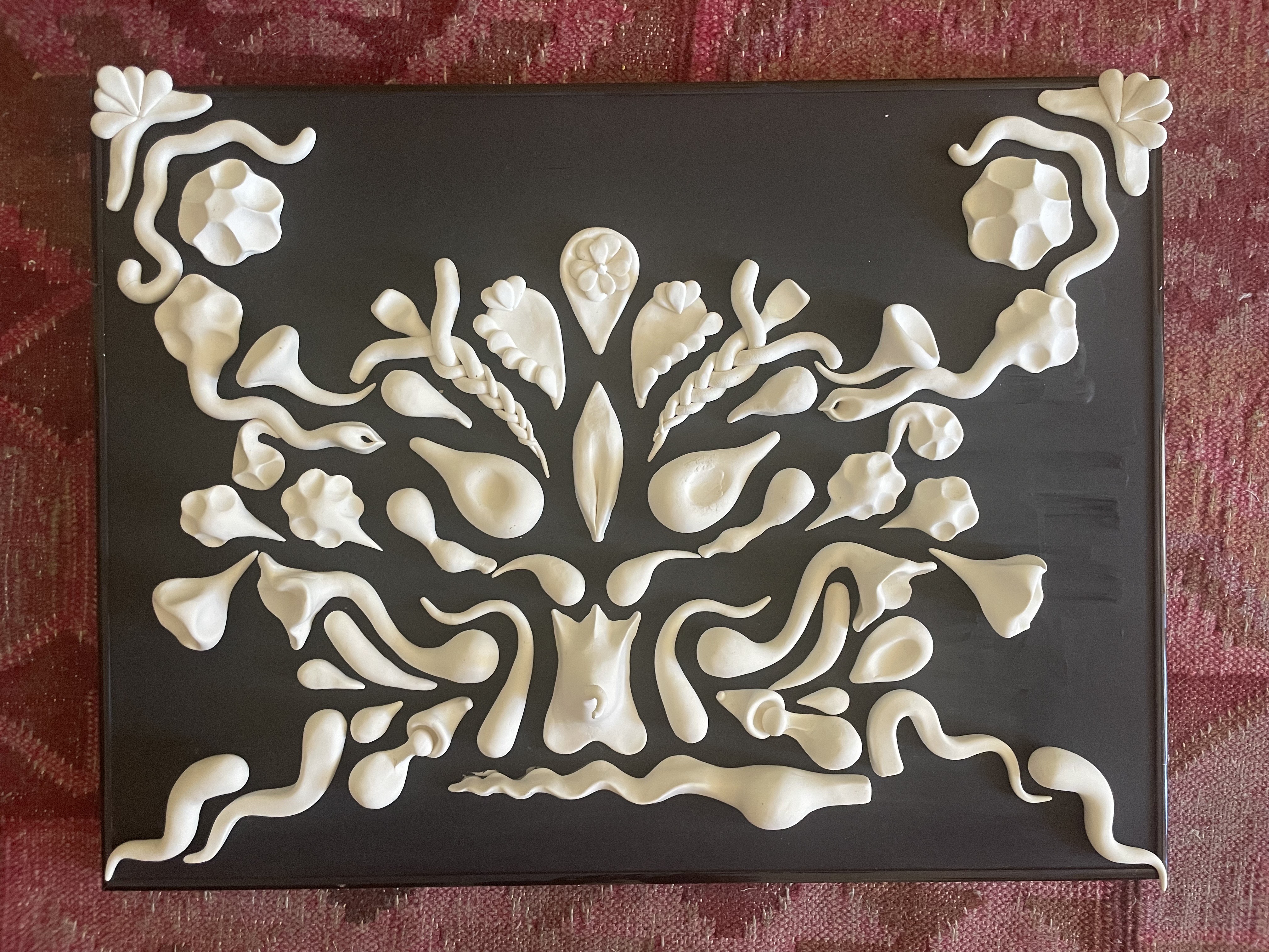 White clay shapes on black glass titled 'Daughter' by Mariah Parvizi