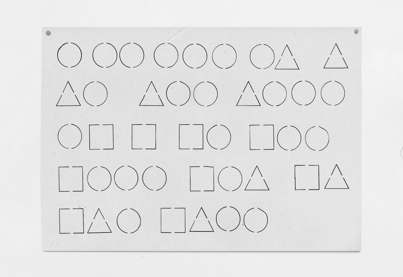 Full de paper reciclat de 297 × 420 mm, de color blanc trencat, amb una seqüència de formes geomètriques (cercle, triangle i quadrat) dibuixades amb línia fina, probablement a partir d’una plantilla stencil. La peça penja d’una paret, subjecta amb dos imants a les cantonades superiors.