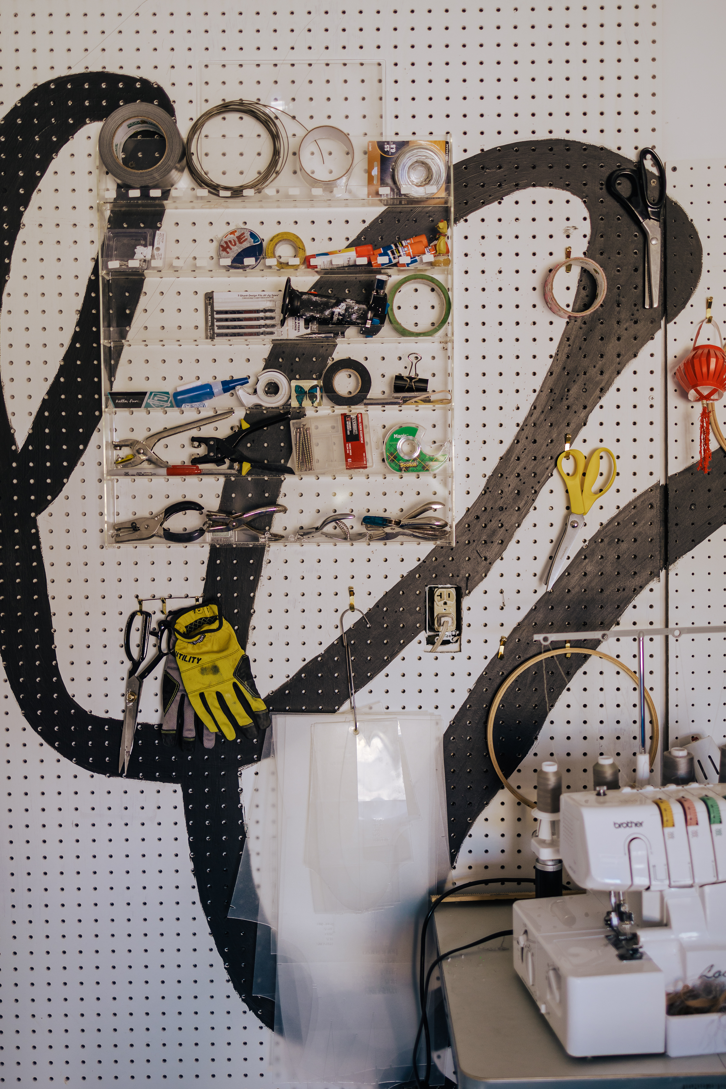 Image taken by Mario Ramirez of the clear tools rack next to the cloud house mending and sewing area where you see scissors, tape, hole punches, embroidery hoops