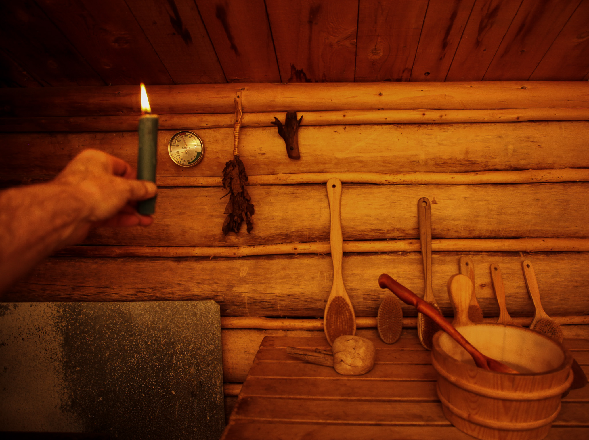 A candle in honor of the Winter Solstice is lit for a moment. The tiny birch whisk on the wall is for the Sauna Tonttu, which in Finnish tradition occupies a well-loved happy sauna. The small driftwood figure symbolizes the presence of a Tonttu. They are to be treated respectfully and honored lest they play tricks on you. There are cautionary tales of sauna fires occurring in the case of grievous offenses or a show of disrespect.