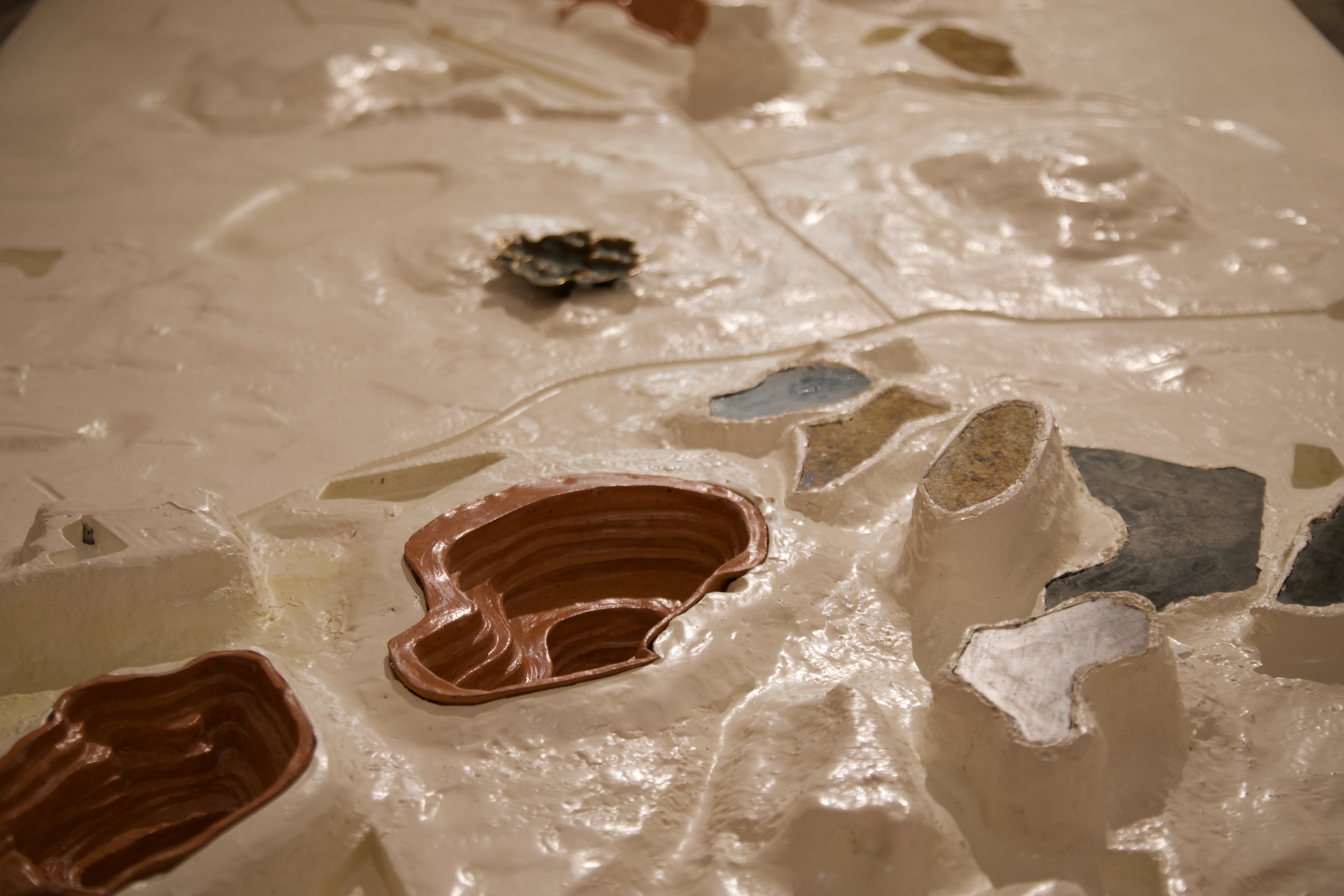 Stepped terracotta bowls rest in the fictive landscape. Stone offcuts mimic cooling ponds and overburden. A cast bronze bowl by Warwick Perrin nestles in the terrain.
