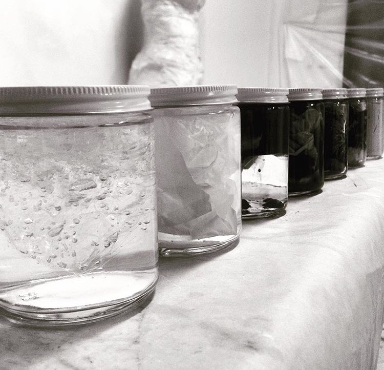 4/4 — OIL AND WATER  6/2 (48 oz. Texas Crude Oil, 16 oz. Illinois Tap Water, remnants of single-use plastic shopping bag).5/3 (40 oz. Texas Crude Oil, 24 oz. Illinois Tap Water, remnants of single-use plastic shopping bag).7/1 (56 oz. Texas Crude Oil, 1 oz. Illinois Tap Water, remnants of single-use plastic shopping bag).Installation view of the project; crude oil, tap water, single-use plastic shopping bags, custom fabricated liquid-tight acrylic; all individual works are 10 1⁄2" x 8 7⁄8" x 1 1⁄2"; 2016.