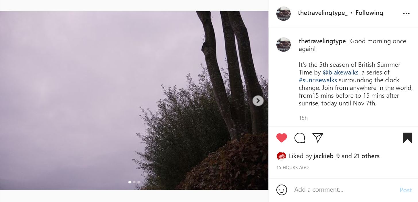 Instagram post by @thetravelingtype with a pink/purple sky and bushes in the right corner. The text reads: Good morning once again!  It's the 5th season of British Summer Time by @blakewalks, a series of #sunrisewalks surrounding the clock change. Join from anywhere in the world, from15 mins before to 15 mins after sunrise, today until Nov 7th.