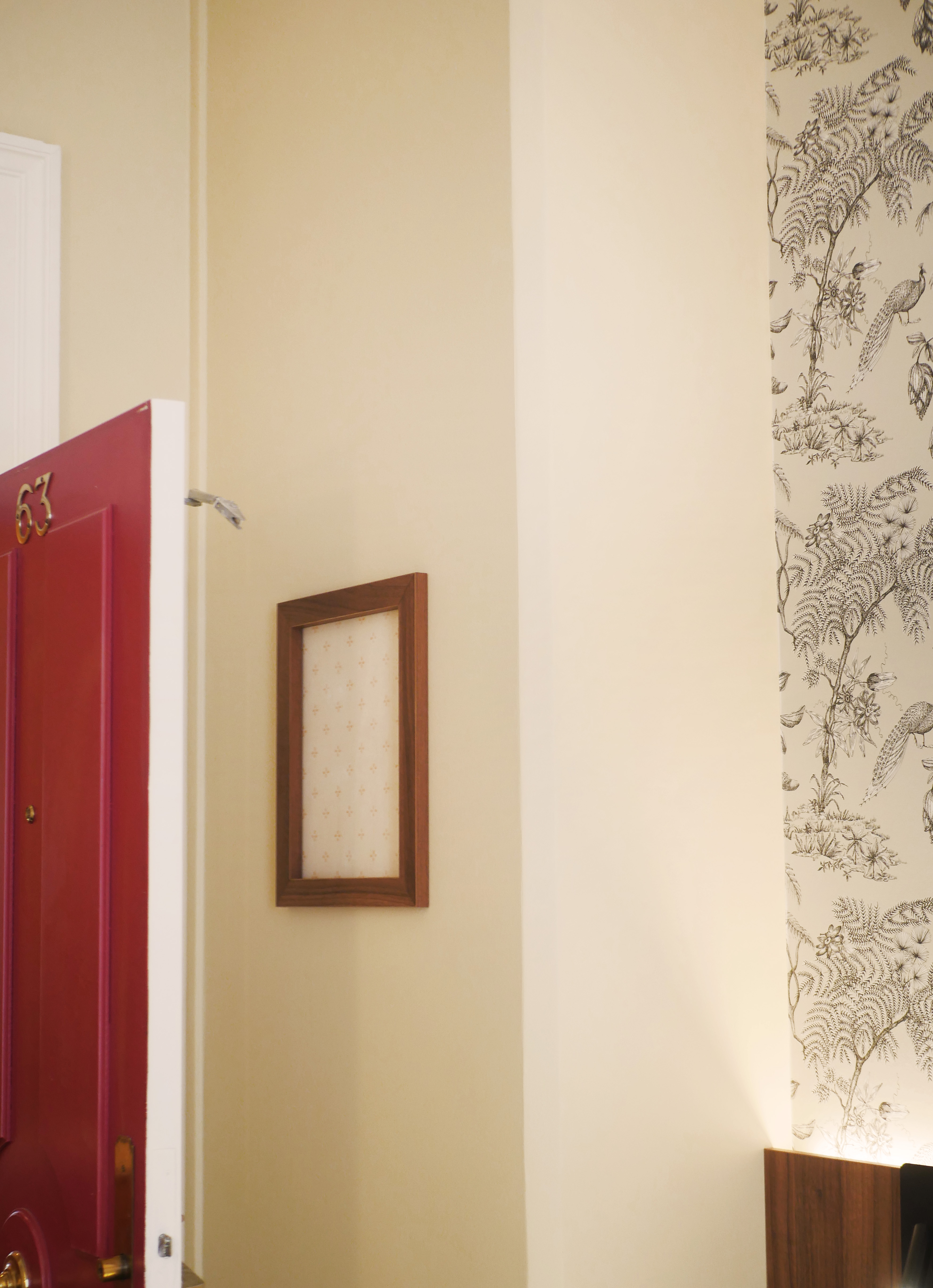 Derrière la porte, un morceau de l'ancienne tapisserie est encadré afin de conserver une trace du passé.