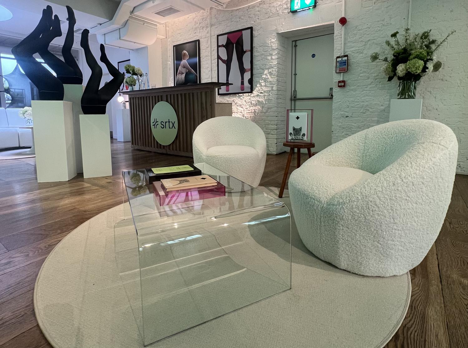 Modern lounge area inside Sheertex activation space with branded counter, leg displays, and seating.