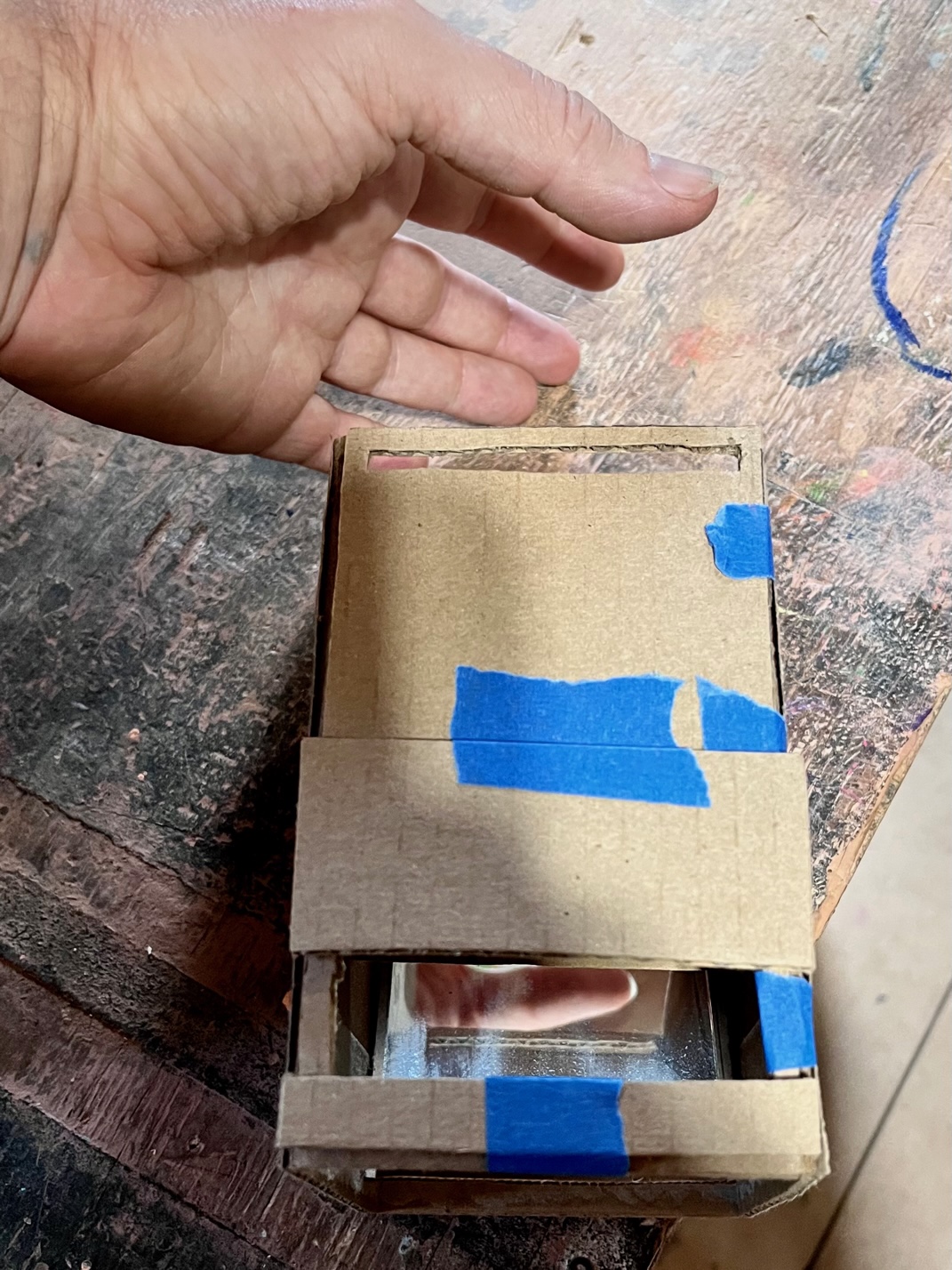 showing you my thumb to see how the mirrors direct the image. You hold the Brownie at chest level and look down into the viewfinder