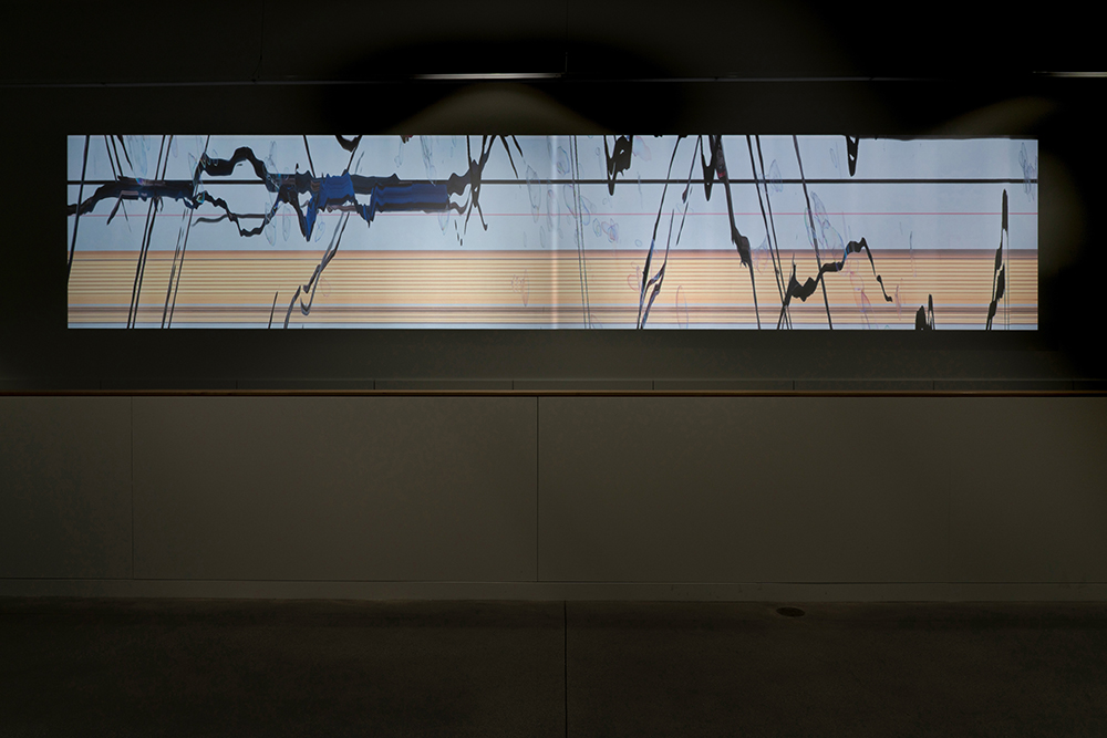 A video projection of abstract lines and patterns in a dark, indoor space.