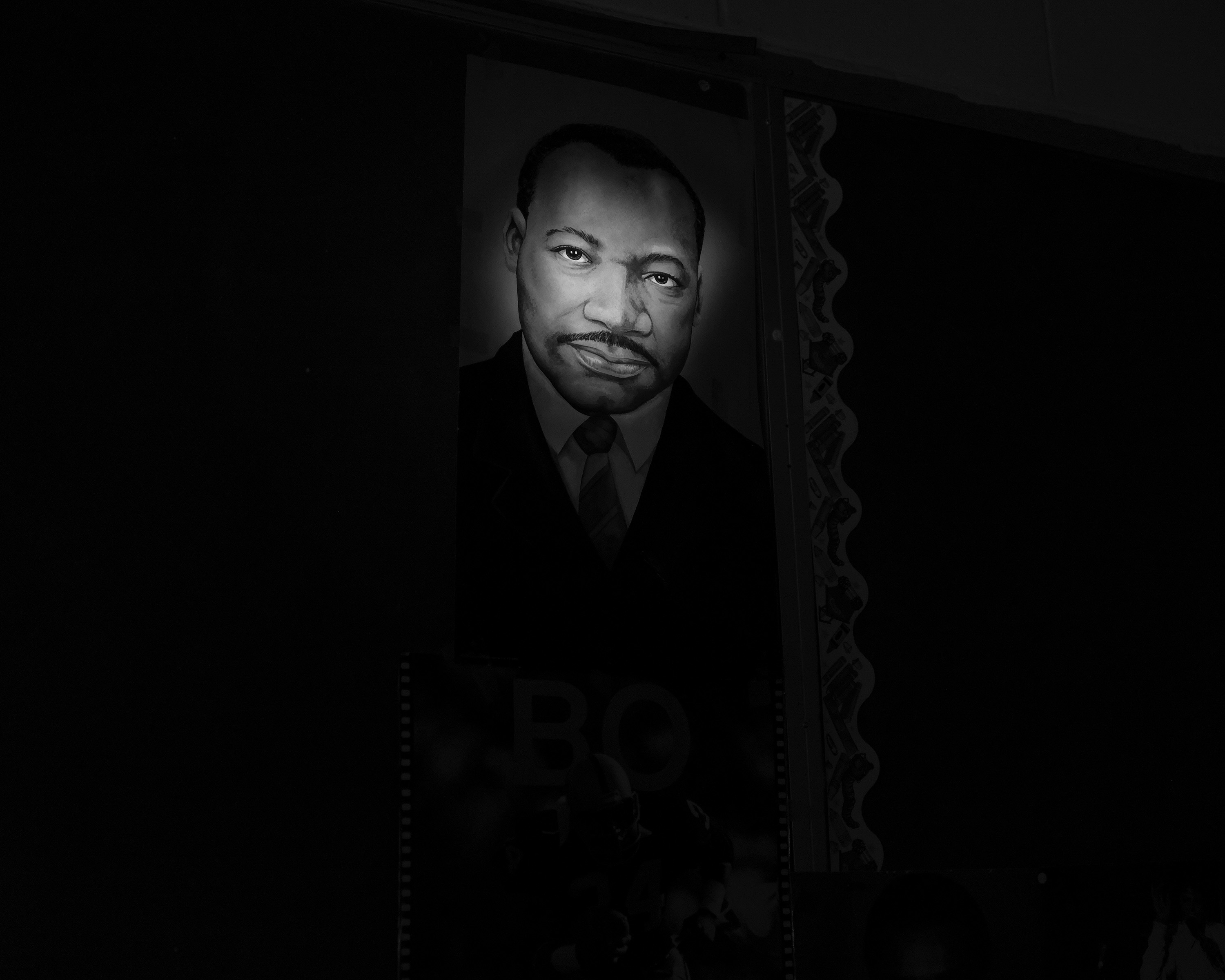 A portrait of Dr. Martin Luther King, Jr. is illuminated by flashlight in the abandoned East Choctaw School in Choctaw Co.