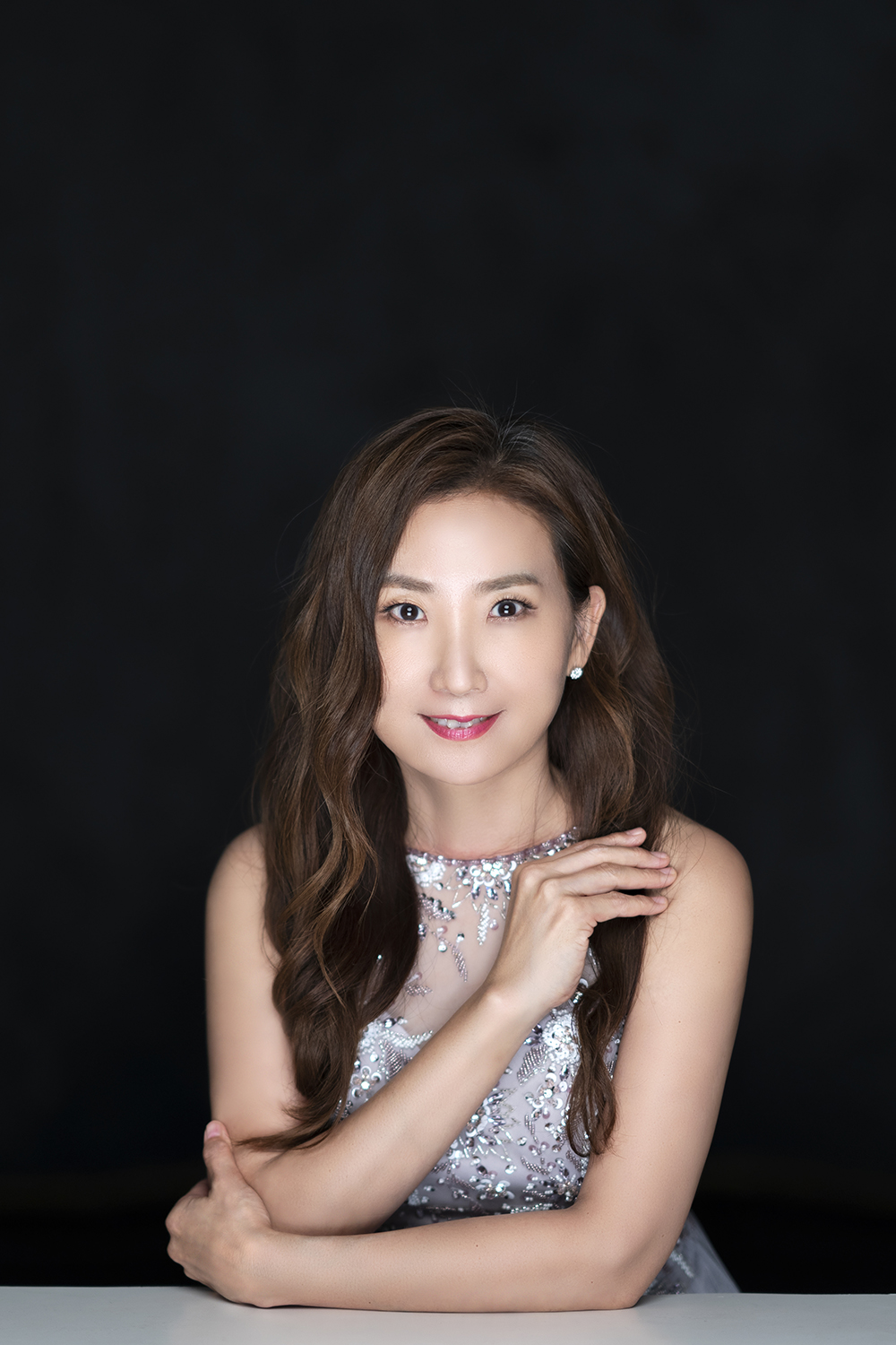 A headshot of pianist Jenny Soonjin Kim with her arms folded and hair down.