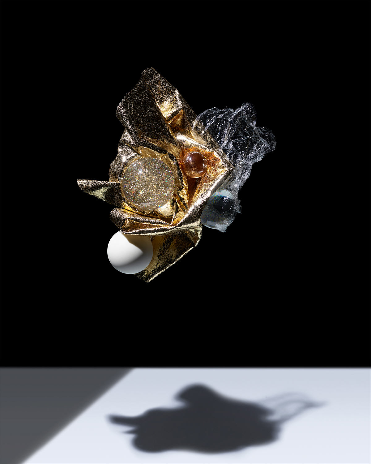 KMA photographer Isabelle Bonjean shoots photograph of floating white and gold objects against black background