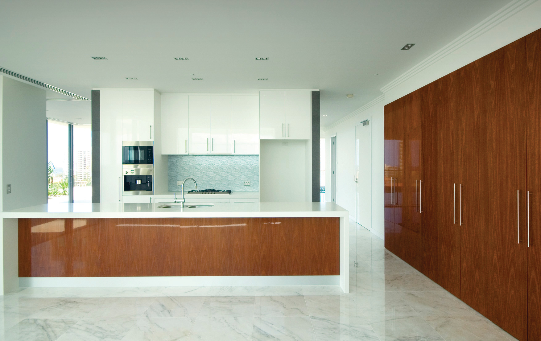 Interior view of a modern apartment kitchen with stone flooring and timber joinery.