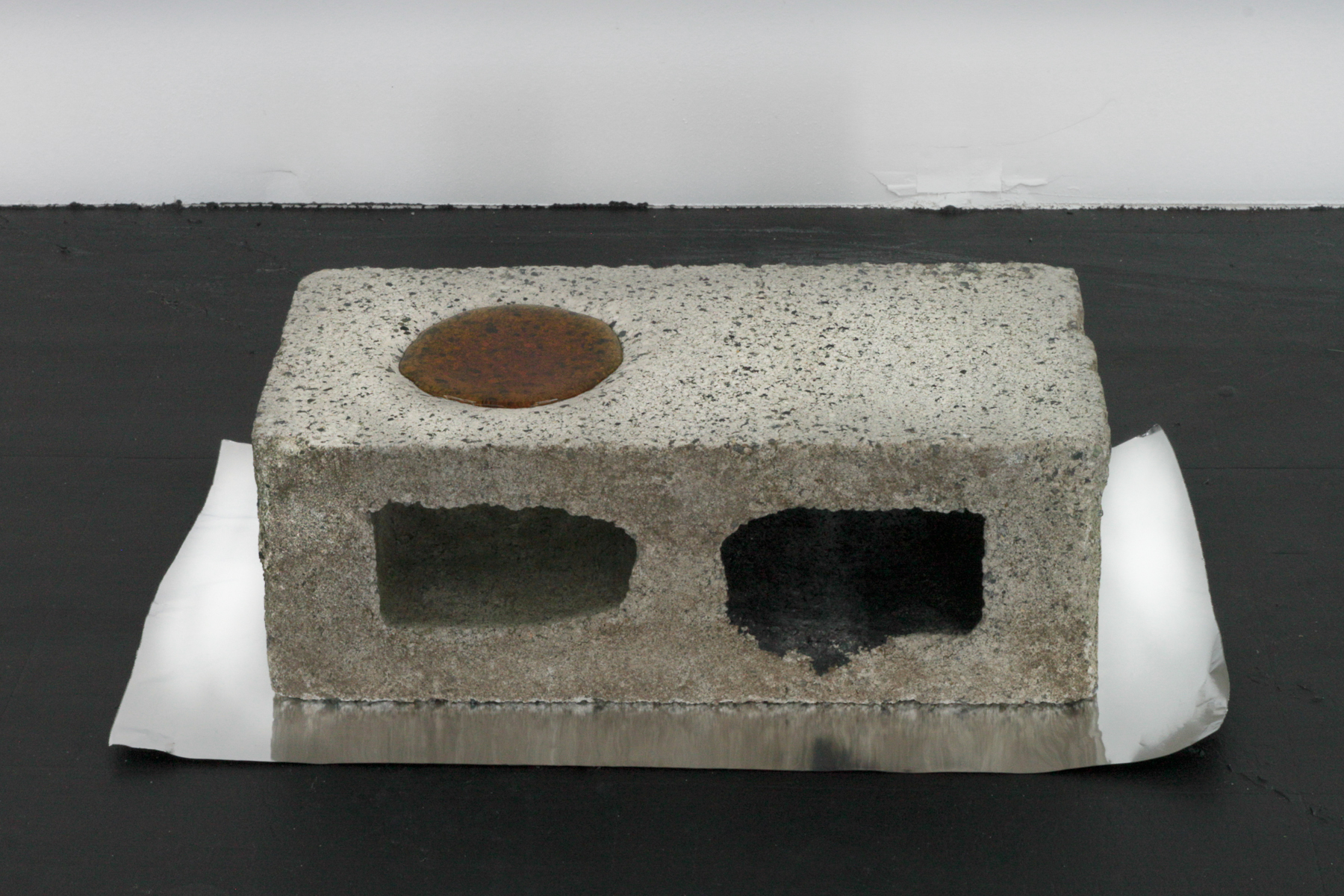 Ablative fluid reduction, 2018, automotive coolant boiled to a reduction, concrete masonry unit, aluminum foil, 6 x 22 x 12 in. (15 x 56 x 30 cm)