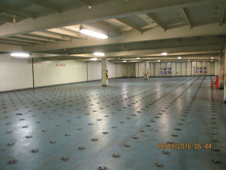 A photo of inside the Atlantic Conveyor, there are metal support beams with yellow and black warning stripes, The metal floor is blue covered in latches. The time stamp reads: "16/09/2016 06:44" 