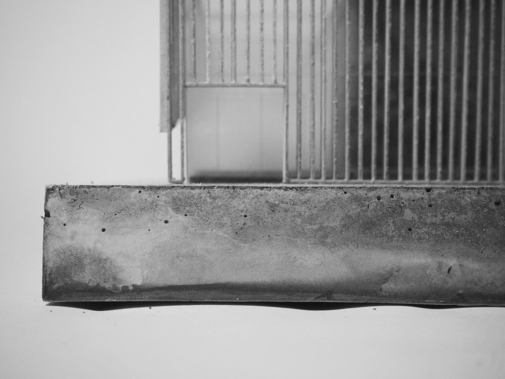 Detail photograph of model, showcasing concrete plinth and wooden screen at entrance.