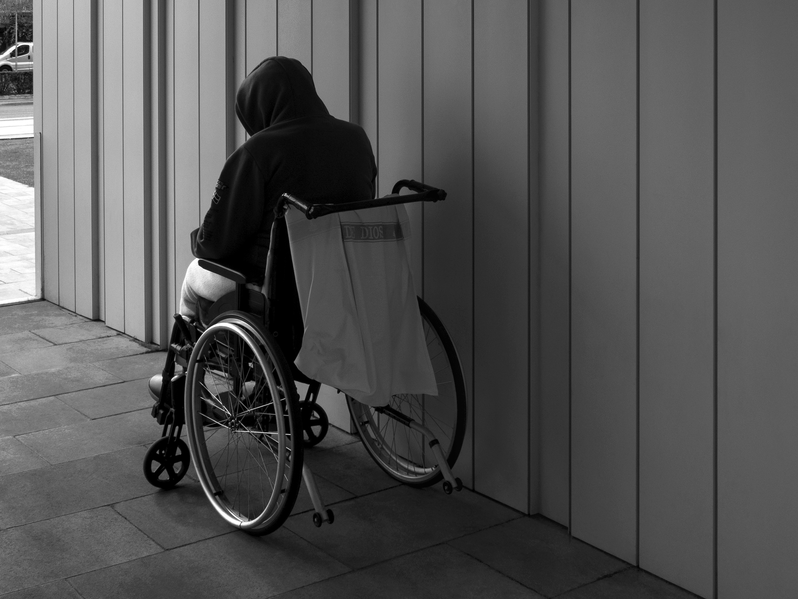 Man in a wheelchair getting some fresh air on the hospital porchPamplona, Spain, 2022photography, bw, single