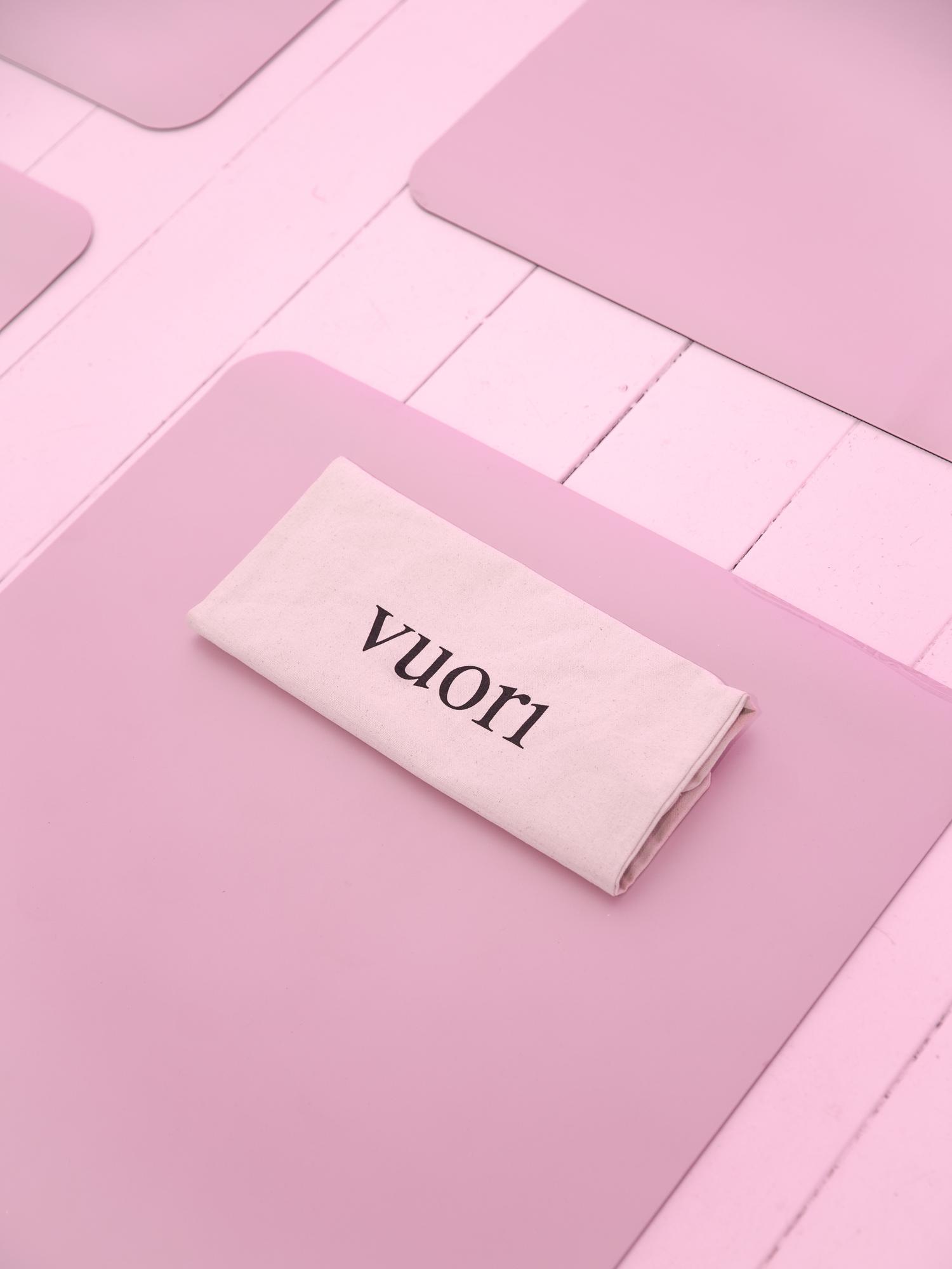 Folded Vuori towel placed on pink yoga mat in bright studio