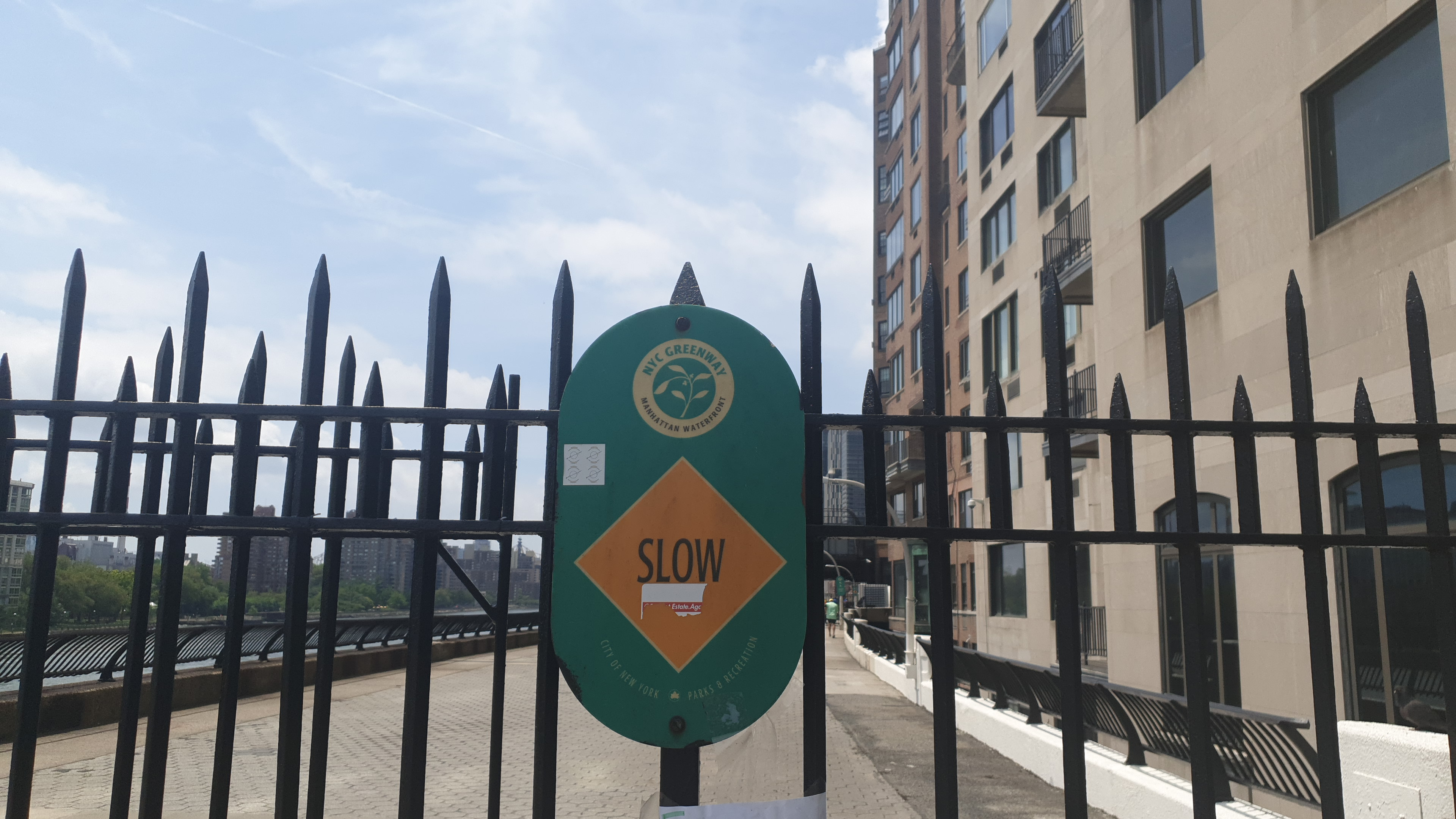 A green sign says Slow on the East River pathway.