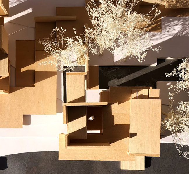 a photo of a wooden model, that from the top view, looks like a dramatic puzzle. the shapes cast really dramatic shadows on the landscape