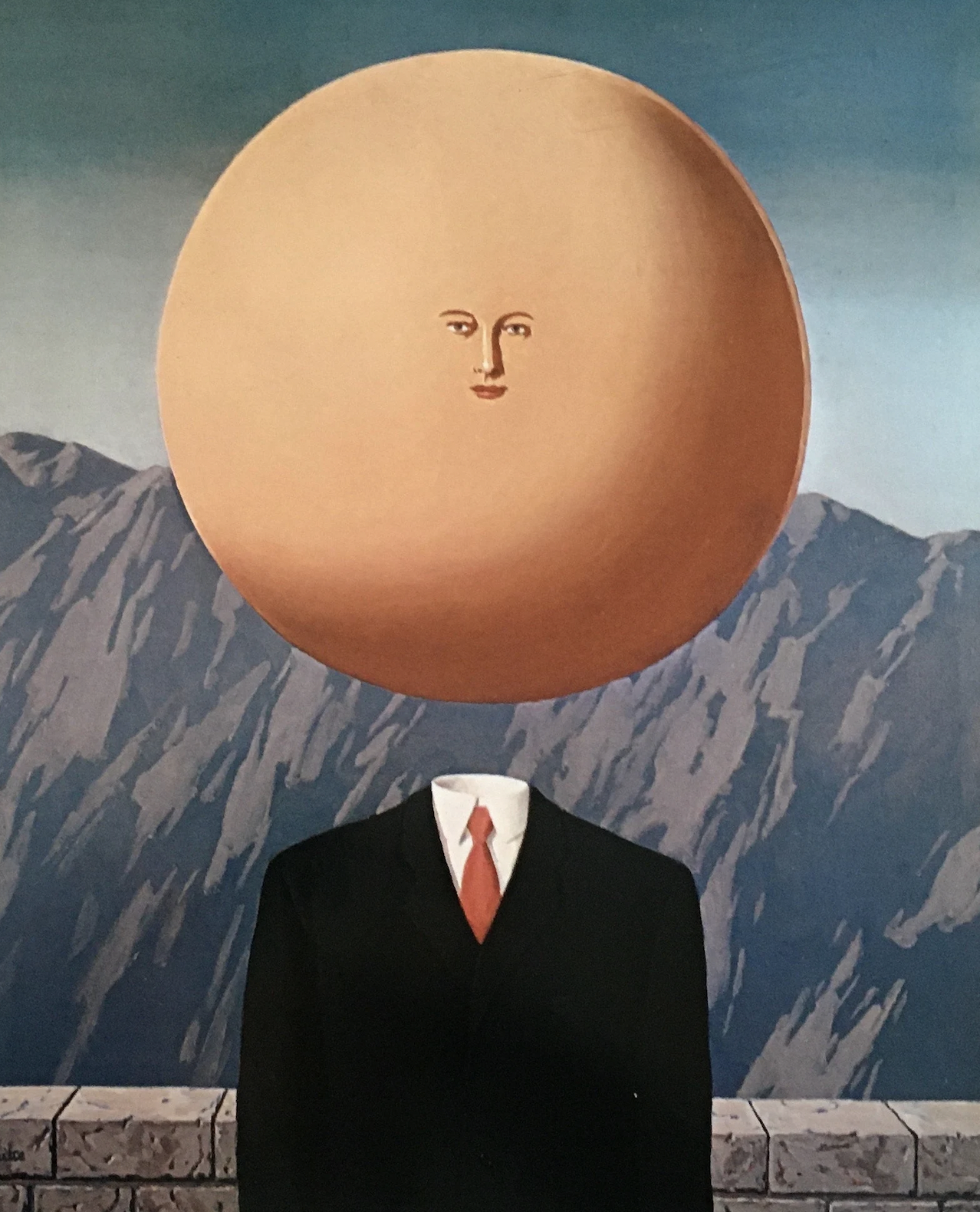 Magritte’s The Art of Living, a surrealist painting of a mans suit and a floating large circular head, with a very tiny face.