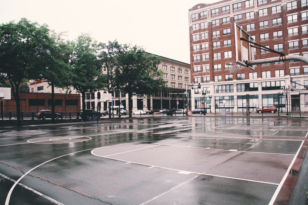 Reggie Wong Memorial Park in Chinatown is a cluster of fenced-in volleyball and basketball courts. Some trees line one side of the park.