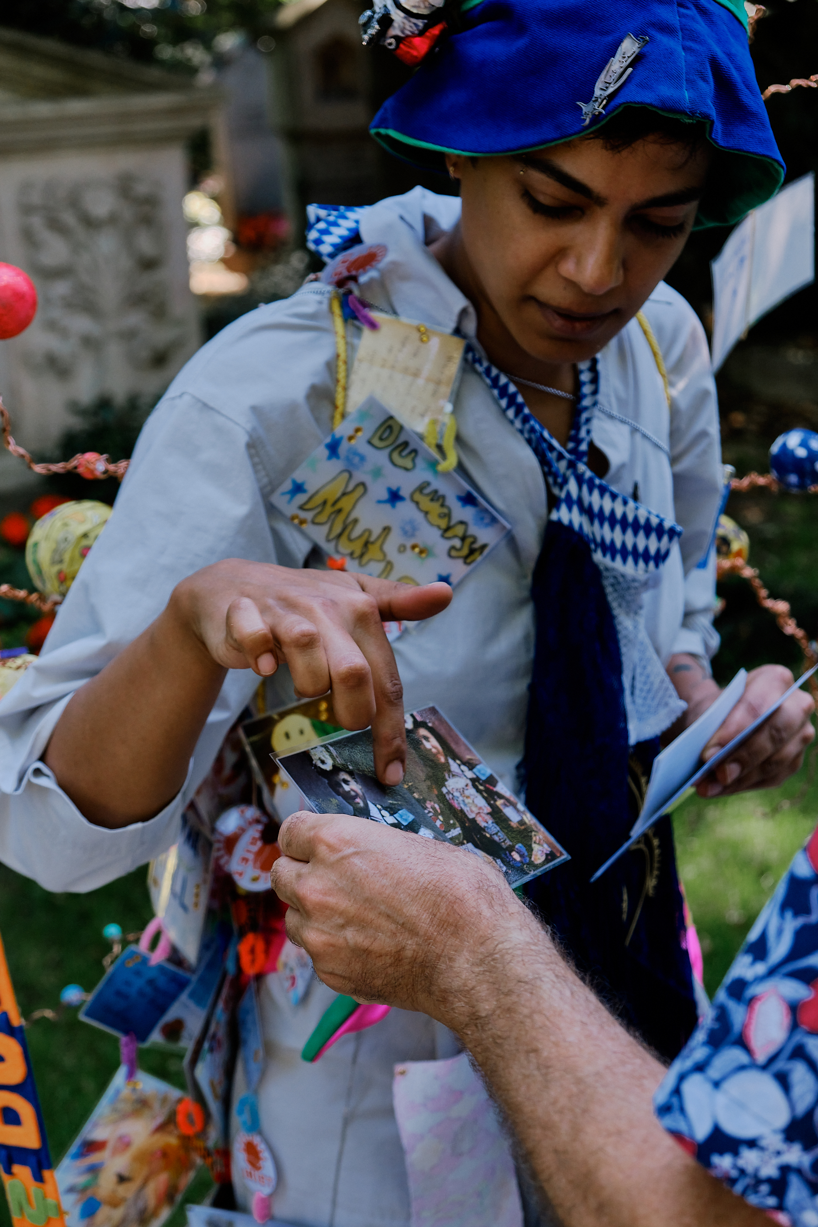 The Memory Person shares a postcard illustration of Karl Valentin's 'Reklamemenschen' with the audience during the interactive city walk. Perfomer: Konouz Saeed. Munich Giesing, 2024. Photograph: Sandra Singh.