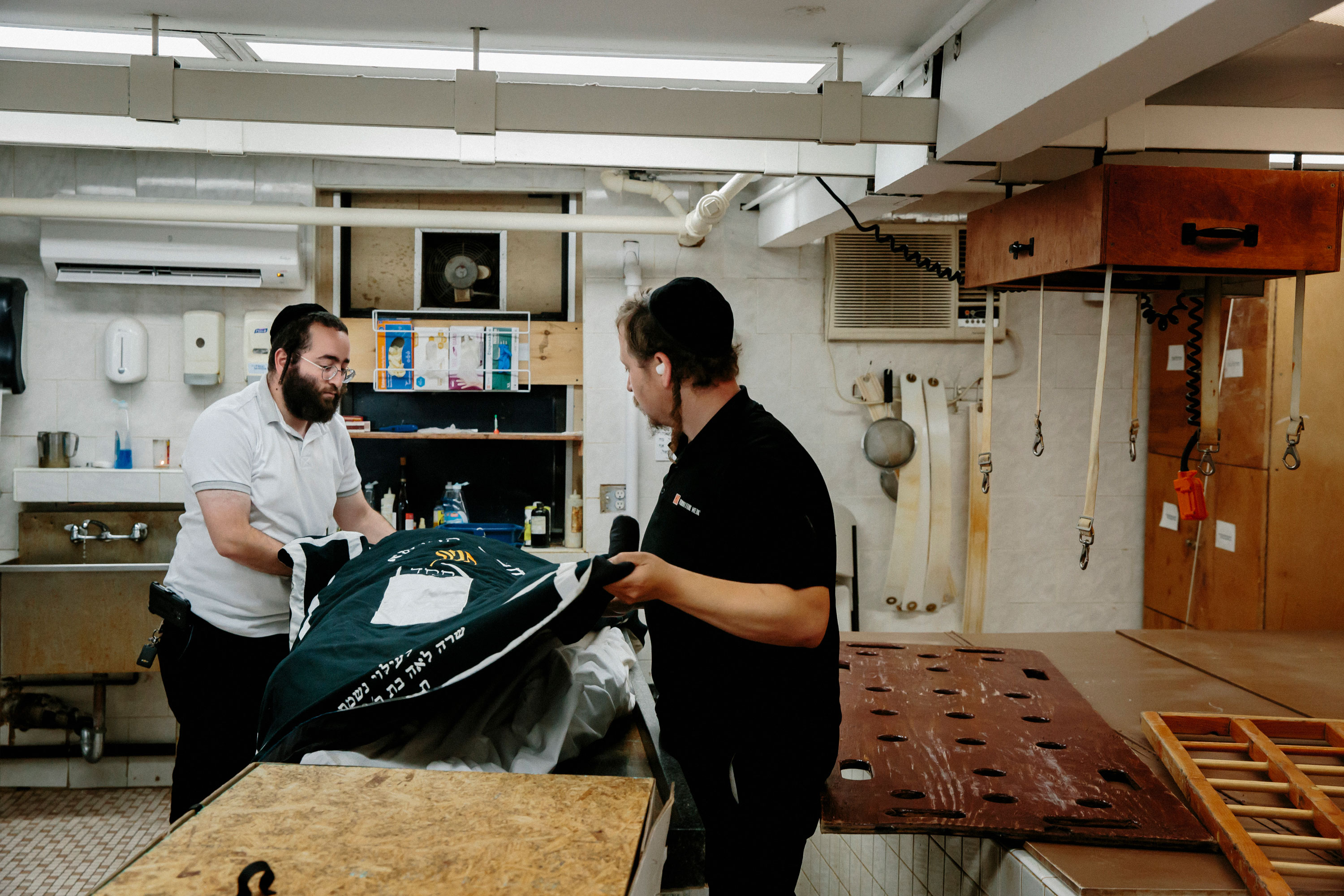 Chaim Oberlander and Shia Weisblum cover the body of the deceased in preparation for a Tahara, or ceremonial bath, at a funeral home in Williamsburg. “Someone has got to do it,” Oberlander said of his post-mortem volunteer work. “Had my first cousin pass away,” Oberlander added. “A 33-year-old, from COVID. He was from Monsey. He left five children and his youngest, his twins, are under a year old. So when it hits, it’s — you know, you’ve got to move on. You know that this is life. Youngsters are the ones that hurt the most.”