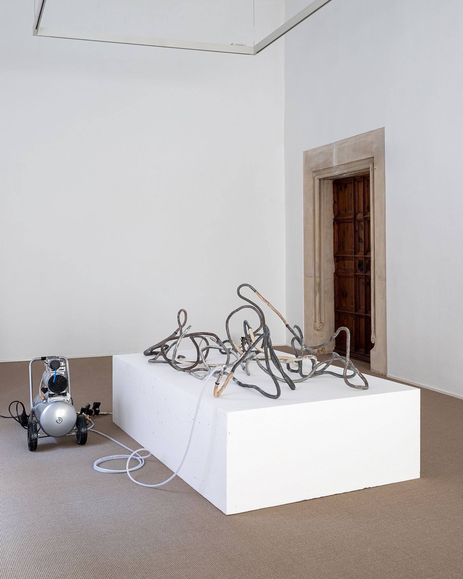 Mallorca 69 (Lead Thread #5), 2025Fragments of lead pipes, pigeon feathers, aluminum tube, MS polymer, rubber O-rings, air compressor, plastic and steel pneumatic components, timed valve, expanded polystyrene, wiring.200 × 185 × 100 cm.Installation view at Processionària,  Galeria Pelaires, Palma, 2024Photo: Juan David Cortés